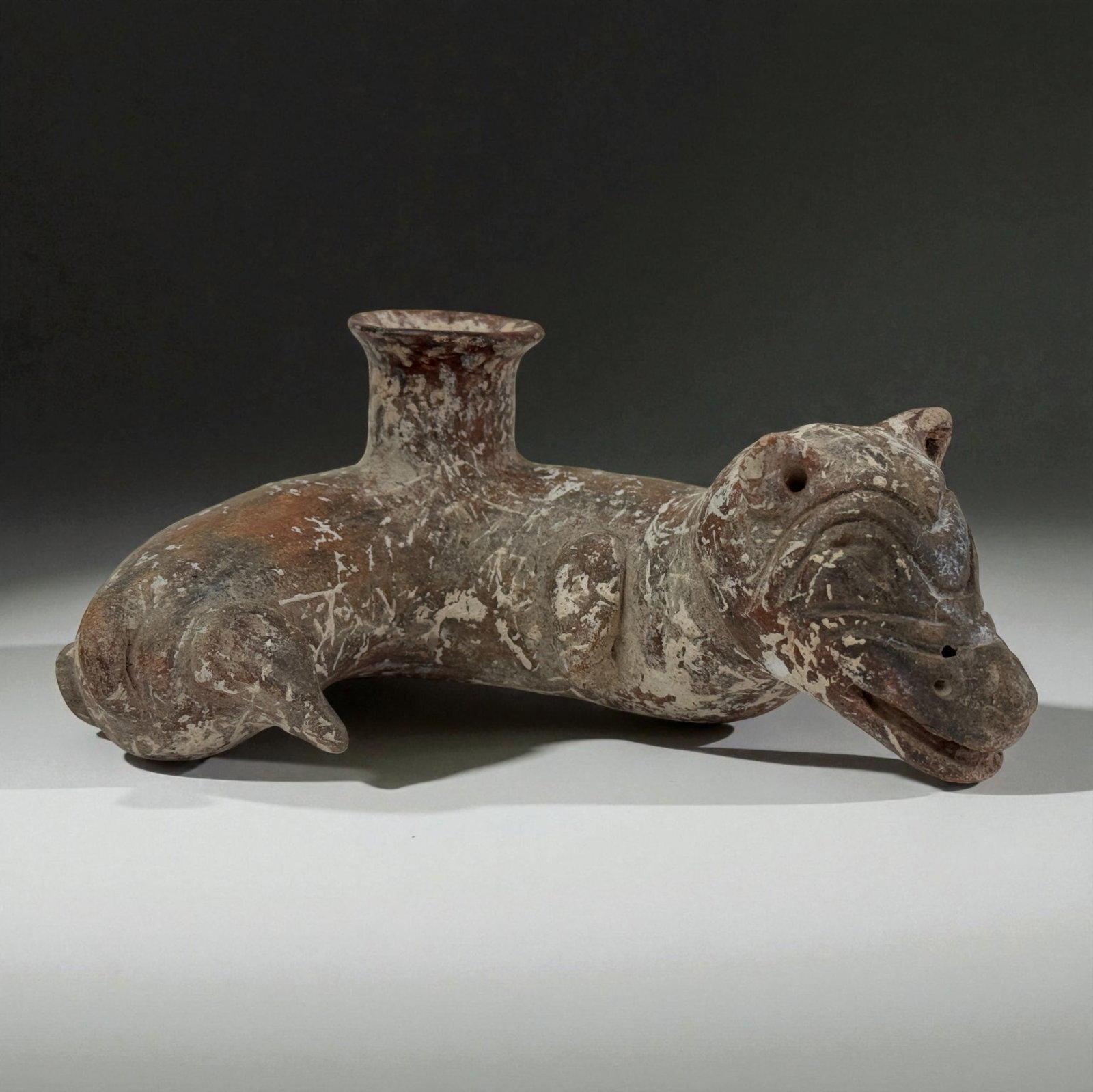 Pre-Columbian Animal Effigy Vessel: Long-bodied animal effigy vessel with expressive face, flaring spout, and weathered red-white slip. Strong personality and sculptural charm. Provenance: Beverly Hills Barakat Gallery Collection. 7 Inc