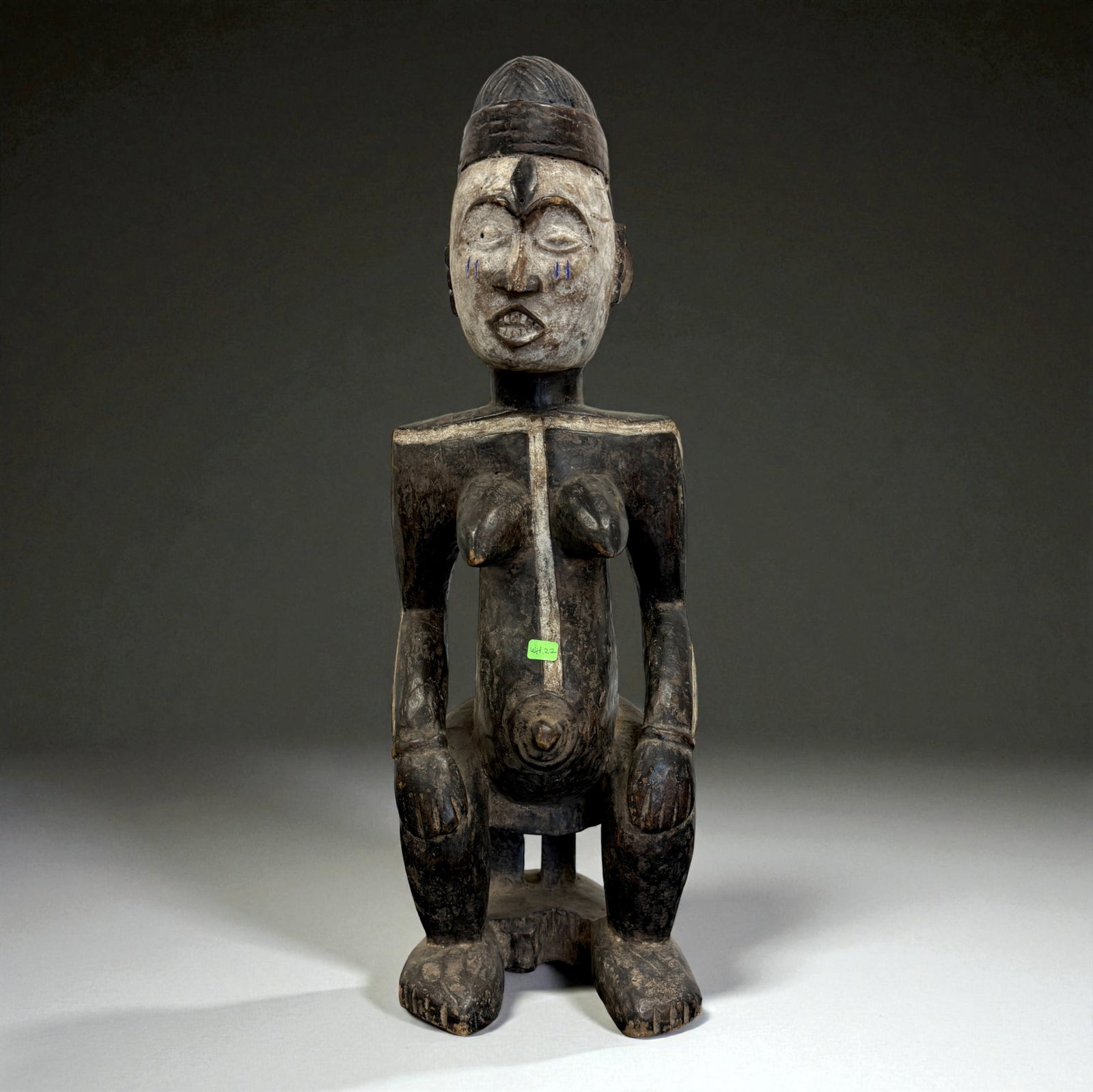 African Carved Female Figure with Pigment: Carved female figure with remnants of white and black pigment, stylized facial features, and seated posture. Likely from West Africa.Provenance: Beverly Hills Barakat Gallery Collection.24" inches