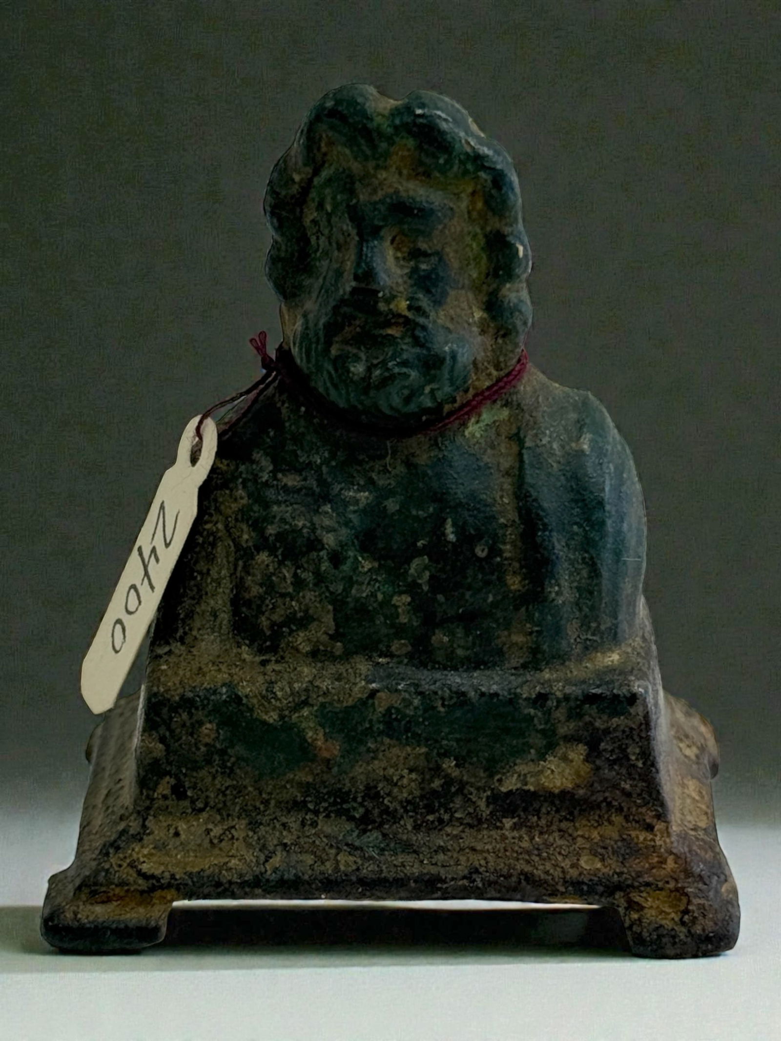 Roman Bronze Bust on Square Base: A Roman bronze bust of a bearded man mounted on an integral square plinth. The figure solemn expression and realistic detail reflect Imperial period craftsmanship. Dark green patina. Culture/Period: R