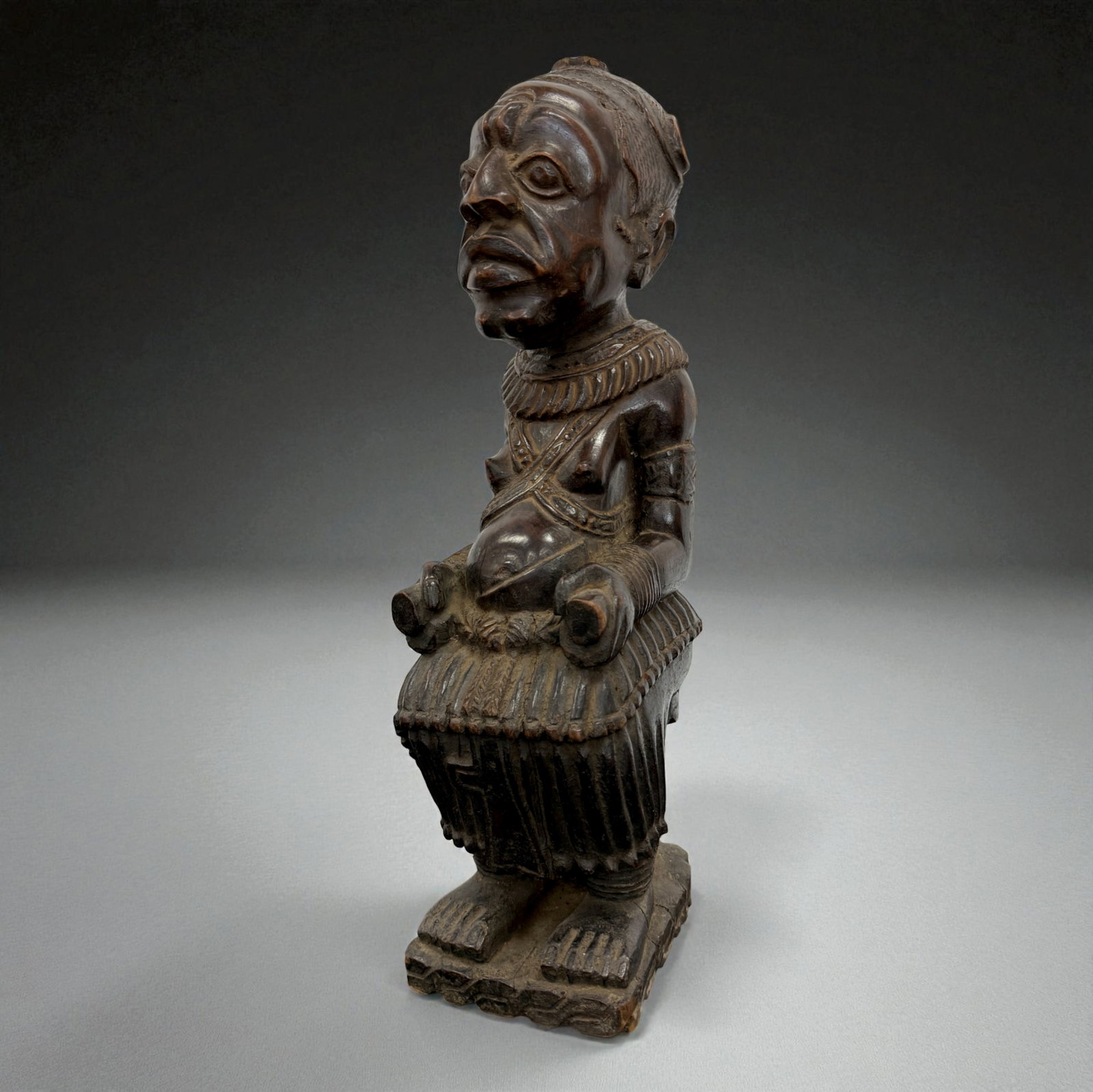 African Seated Female Figure ? Congo Region: Carved wooden seated matriarch figure with detailed facial features and body ornamentation. 19th?20th Century. Provenance: Beverly Hills Barakat Gallery Collection. 20" inches
