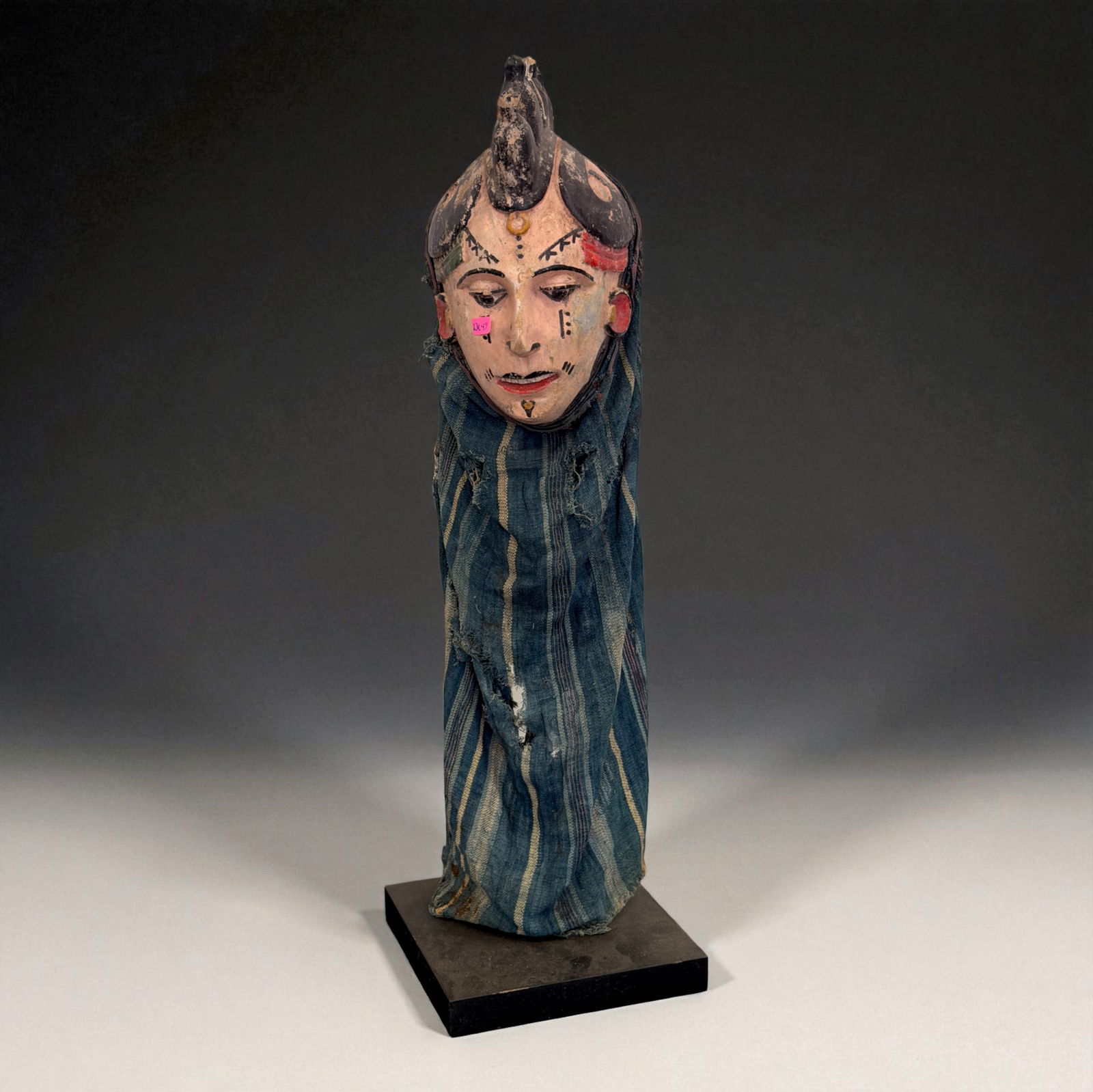 African Painted Wooden Head Figure: Painted wooden head figure wrapped in traditional cloth, with facial markings and ritual coloration. Mounted on base. Provenance: Beverly Hills Barakat Gallery Collection. 10"
