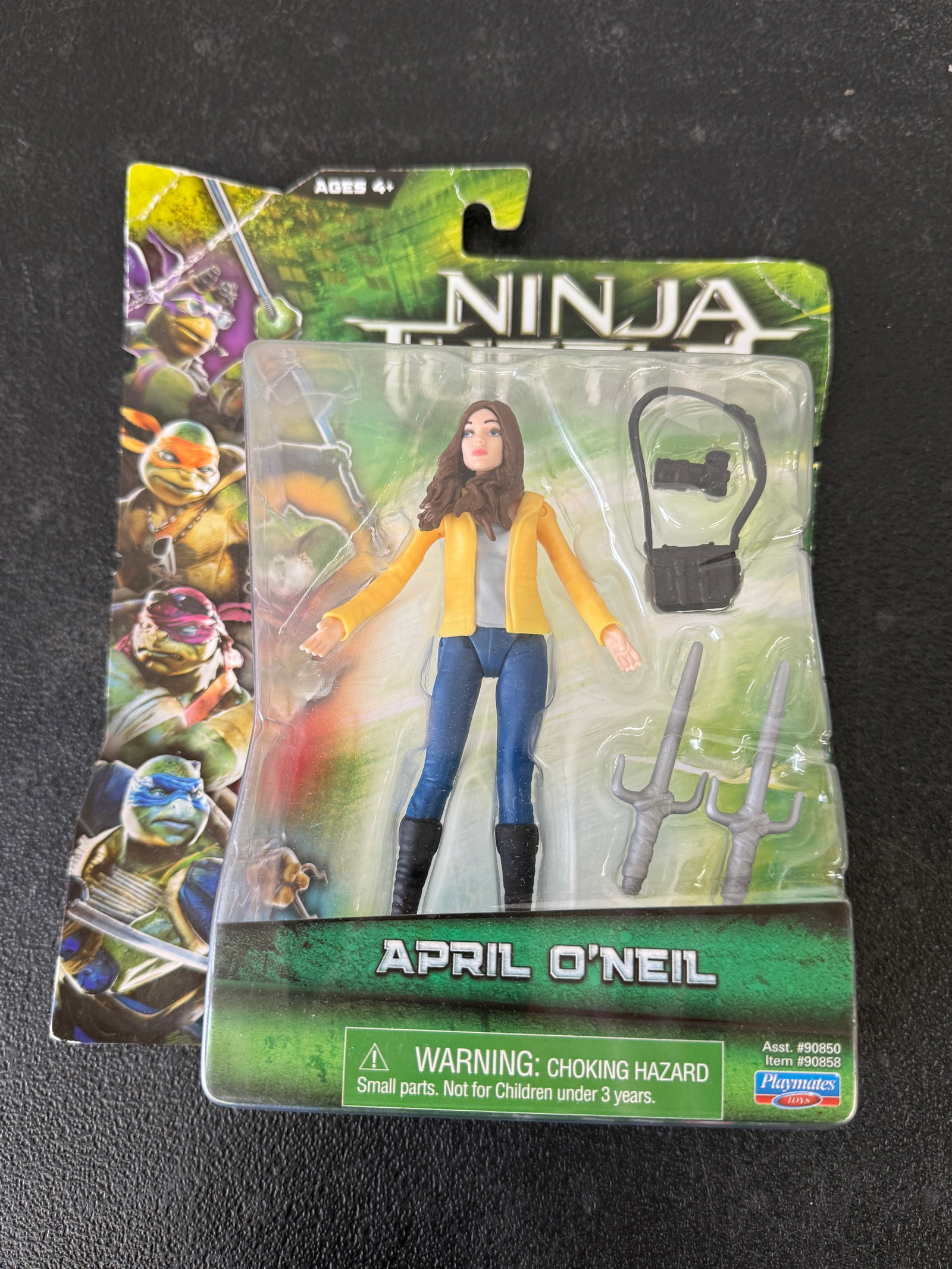 Teenage Mutant Ninja Turtles April O'Neil Action Figure Playmates 2014 MOC: This is an officially licensed April O'Neil action figure from the 2014 Teenage Mutant Ninja Turtles live-action film, produced by Playmates Toys (Item #90858, Assst. #90850). The figure depicts April