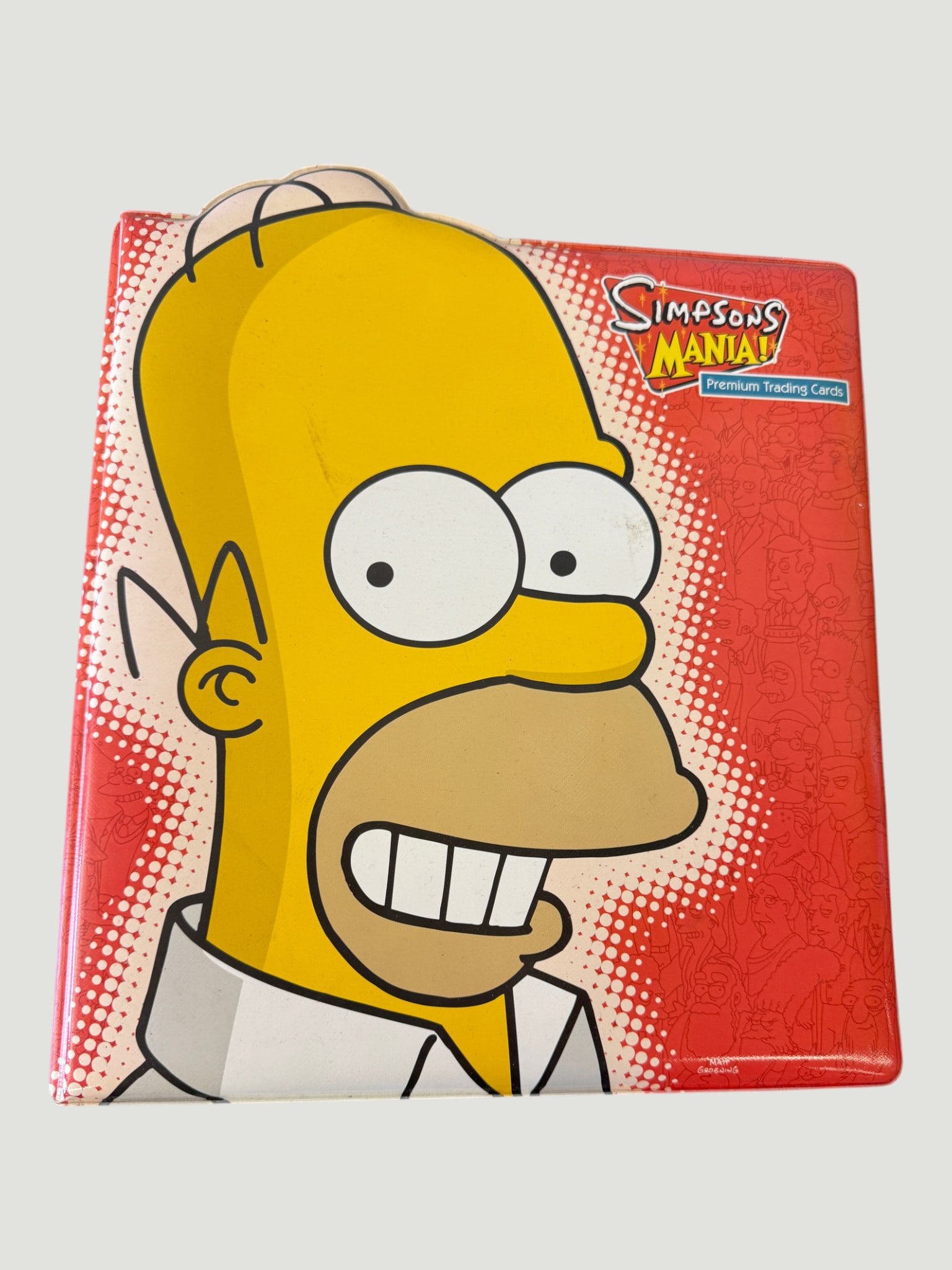 Simpsons Mania! Premium Trading Cards Collector Binder — Homer Simpson: A Simpsons Mania! Premium Trading Cards collector binder featuring a bold graphic of Homer Simpson on the cover against a red halftone background. Published under license from Twentieth Century Fox, t