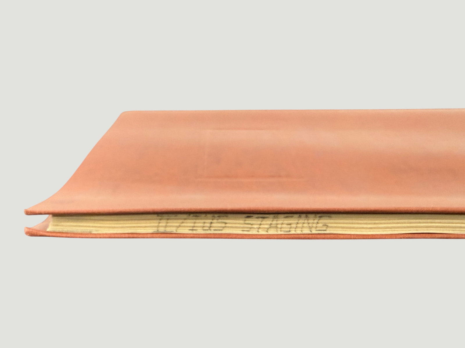 Iliad / Ilios Staging Handwritten Manuscript Notebook, Salmon Leather Cover: A handwritten manuscript or working notebook with a salmon/terracotta colored soft leather cover, containing pages with text relating to 'Ilios Staging' or staging notes for a production or adaptation