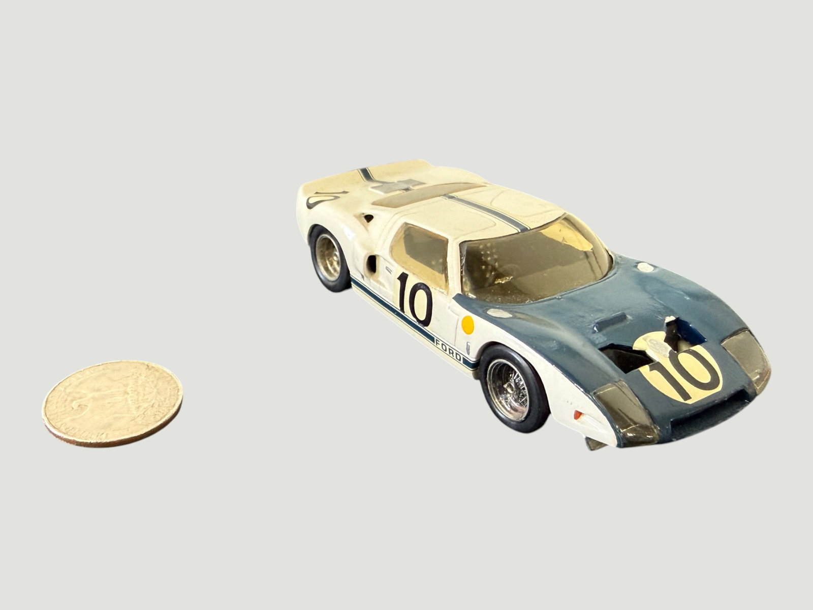 Ford GT40 #10 White/Blue Die-Cast Scale Model Racing Car with Coin: A die-cast scale model of the iconic Ford GT40 Le Mans racing car, finished in the classic white and Gulf-blue livery with racing number 10 markings on both the door and nose. The model features detai