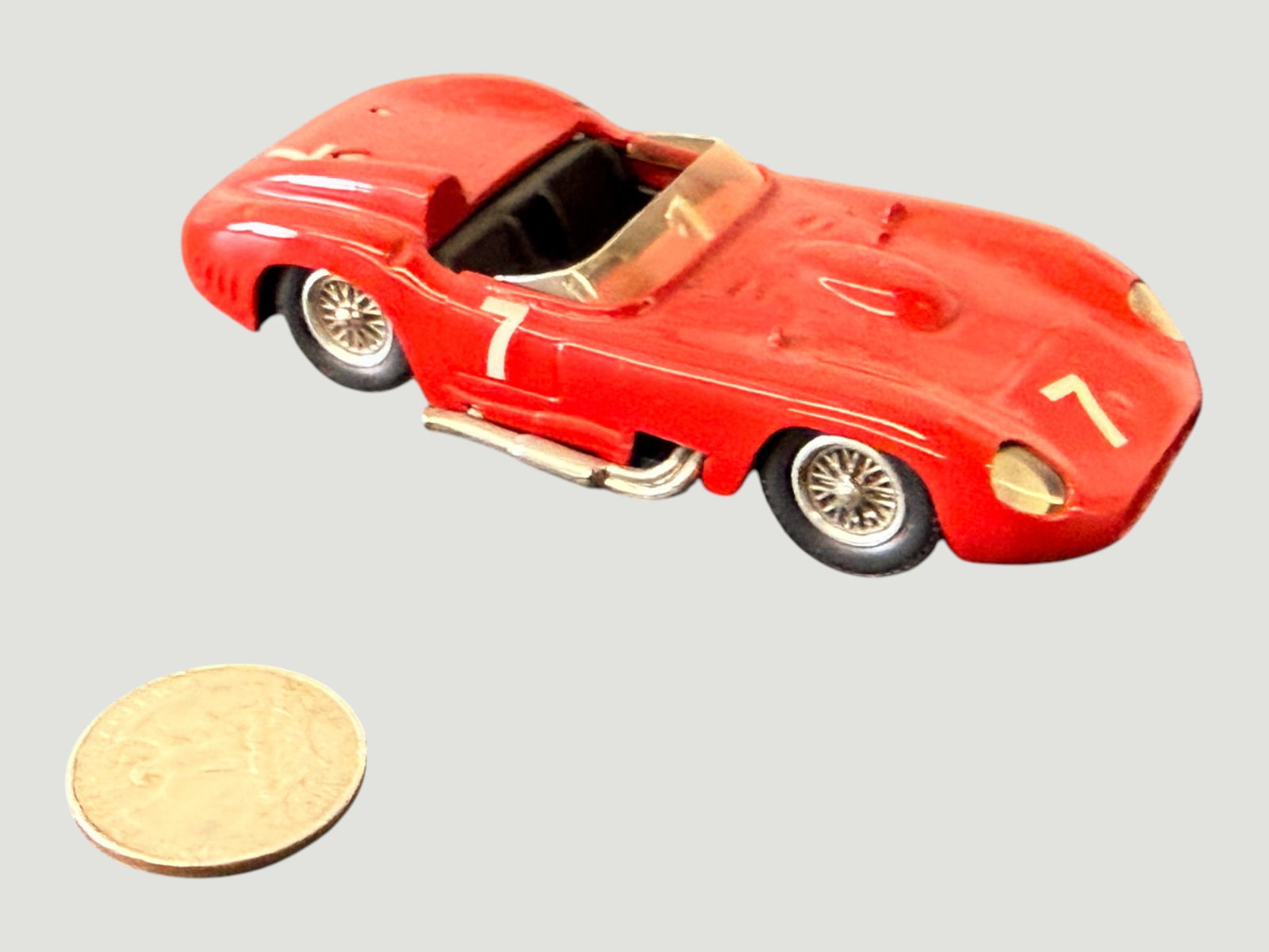 Vintage Diecast Ferrari Racing Car Model #7 Red Sports Racer 1:43 Scale: A vintage diecast metal model of a Ferrari racing sports car, finished in classic Scuderia Ferrari red with race number '7' markings on both the nose and side bodywork. The model features detailed wir