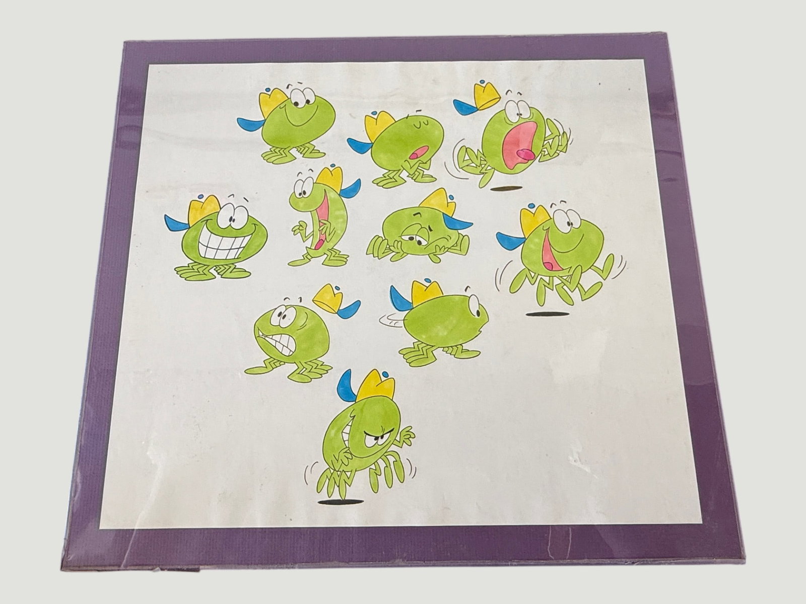 Original Animation Cel Art - Green Frog Character Model Sheet, c.1980s-90s: A hand-coloured character model sheet featuring a green cartoon frog character depicted in approximately nine different poses and expressions, including happy, angry, surprised, laughing, and jumping 
