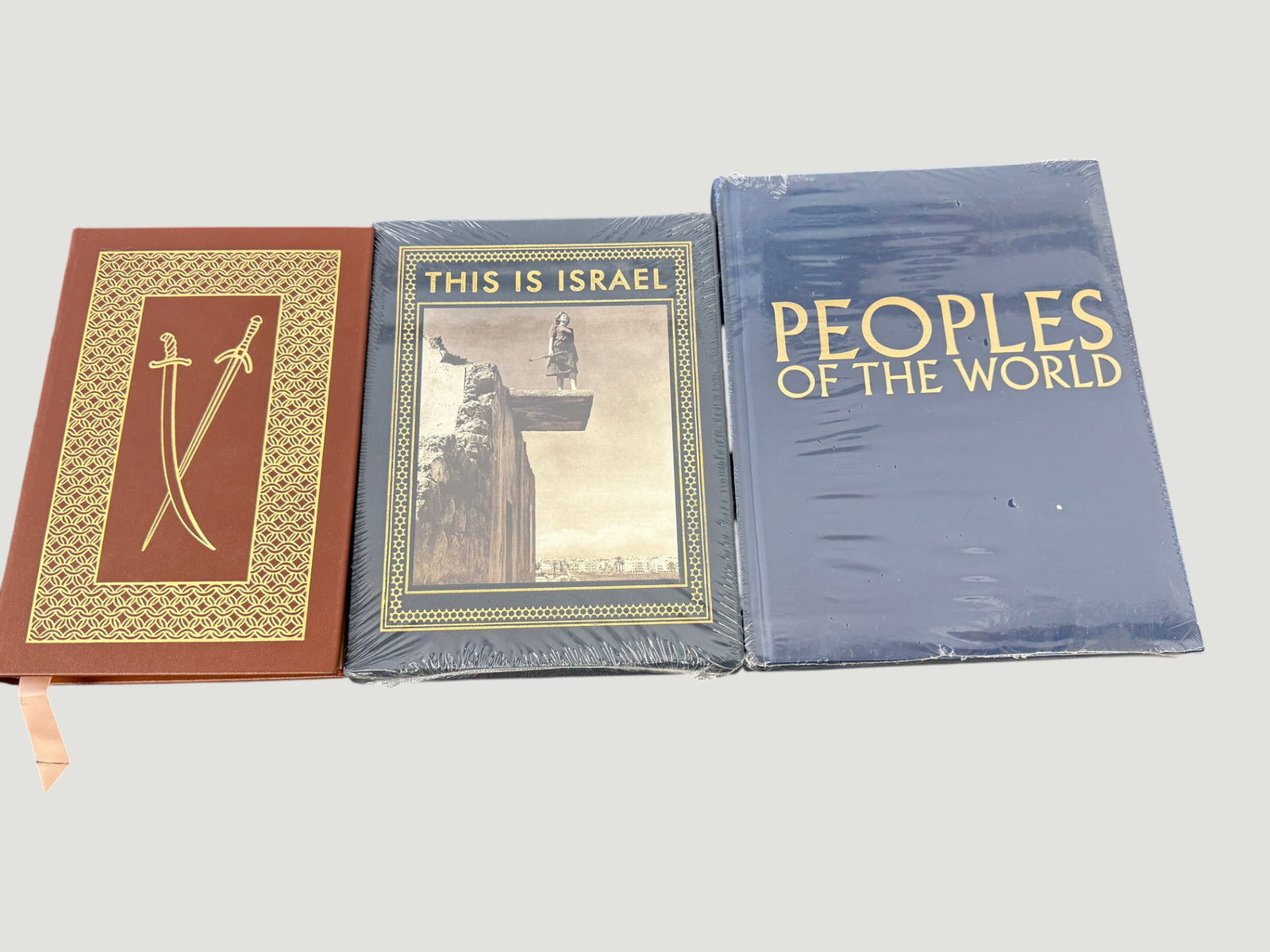 Collection of 3 Hardcover Books: This Is Israel, Peoples of the World & Swords: A collection of three hardcover books comprising: 'This Is Israel,' a vintage photographic volume featuring evocative black-and-white imagery with decorative gold-bordered cover; 'Peoples of the World
