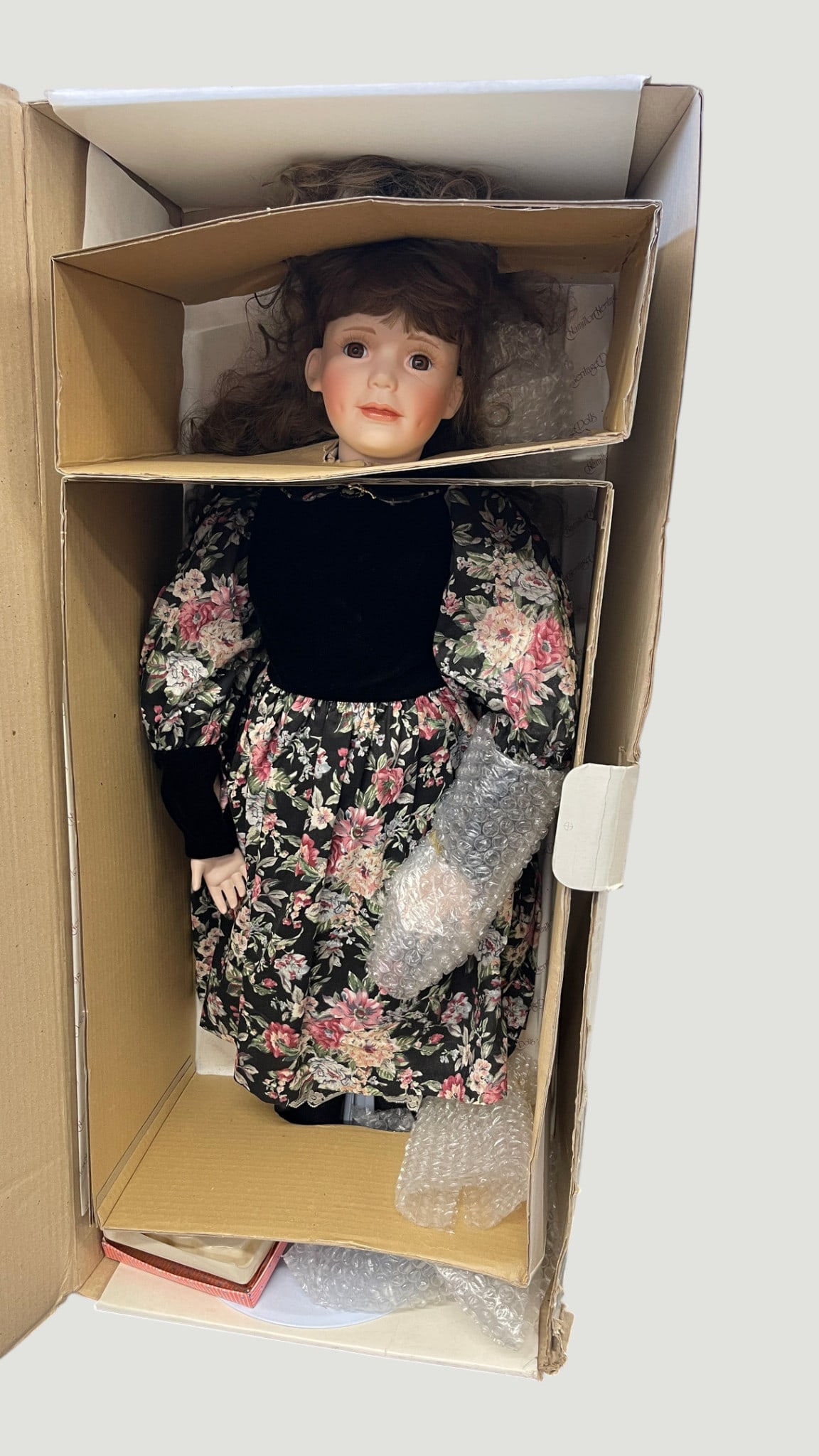 Large Porcelain Collector Doll in Floral Dress, approx. 24", Original Box: A large porcelain collector doll standing approximately 24 inches tall, featuring a bisque porcelain head with hand-painted facial features, rosy cheeks, brown glass eyes, and curled auburn hair. The 
