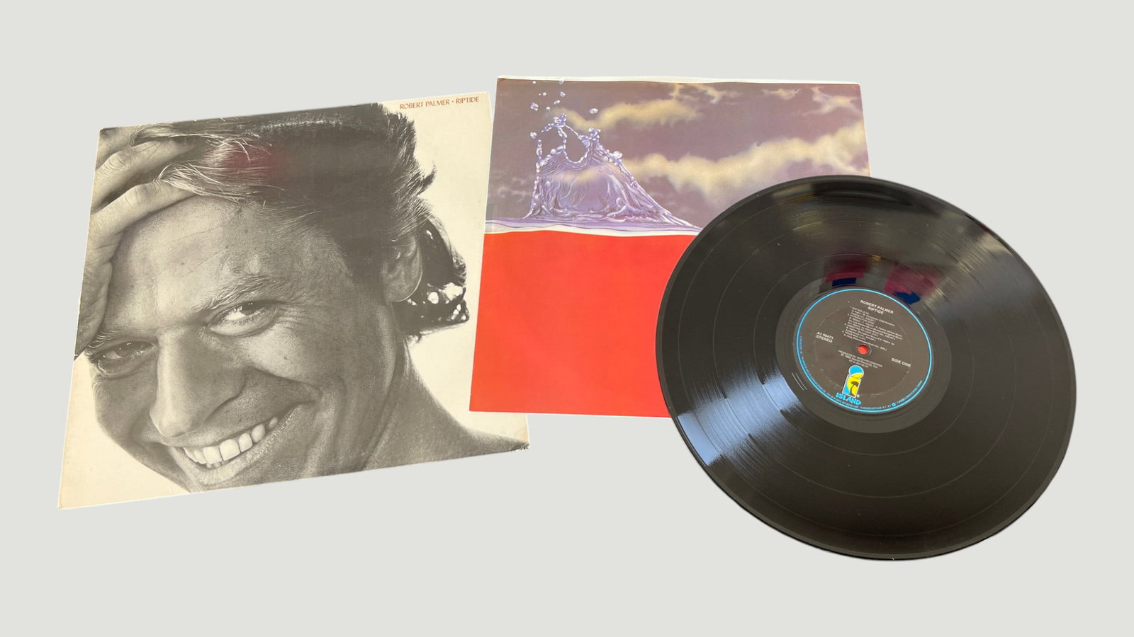 Robert Palmer – Riptide LP Vinyl Record, Island Records, 1985: Robert Palmer's seventh studio album 'Riptide', released in 1985 on Island Records (catalog AT 90471), presented here as a 12-inch vinyl LP with original inner sleeve. The album features the iconic hi