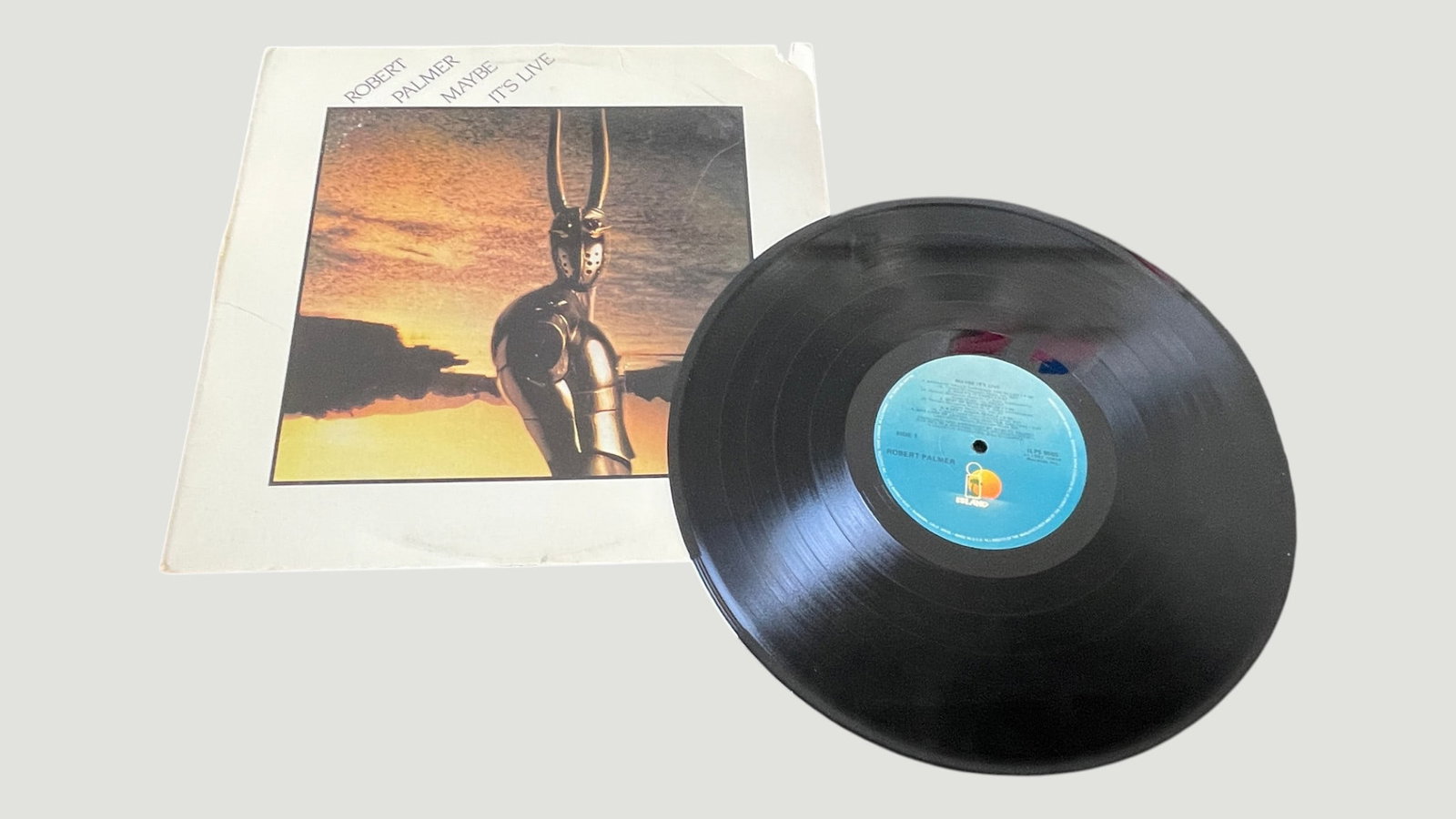Robert Palmer 'Maybe It's Live' Vinyl LP – Island Records, 1982: A vinyl LP pressing of Robert Palmer's live album 'Maybe It's Live,' released in 1982 on Island Records. The record features the iconic armored figure artwork on the cover and bears the distinctive Is