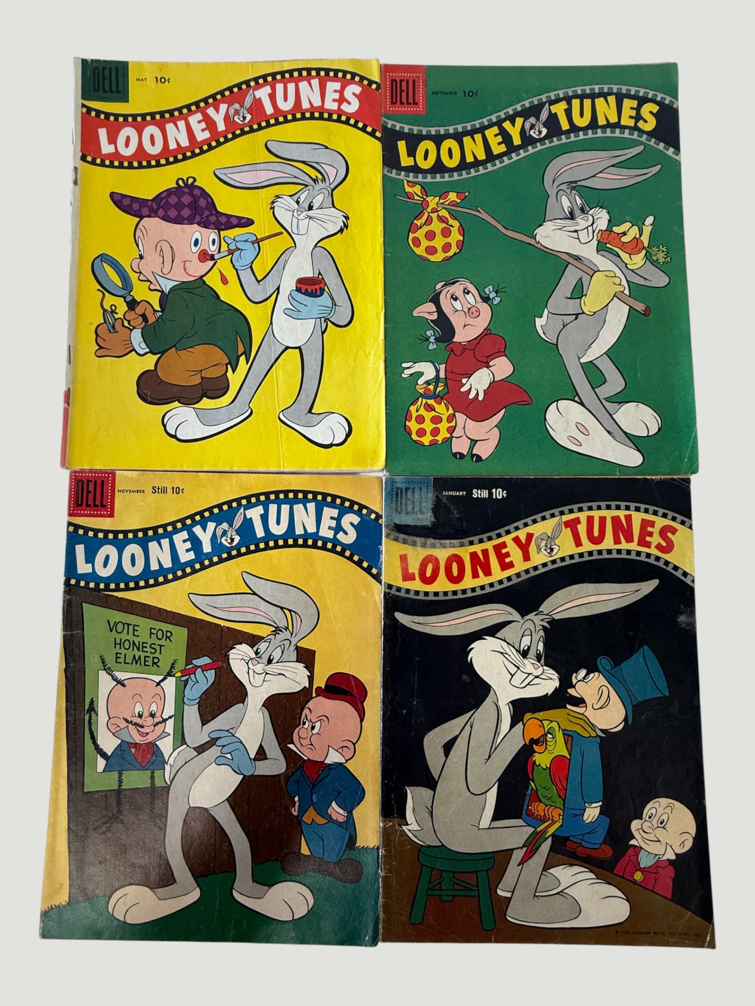 Dell Looney Tunes Comics x4 — May, Sept, Nov, January Issues — Bugs Bunny Era: A group of four Dell Publishing Looney Tunes comic books, priced at 10 cents each, featuring Bugs Bunny and Elmer Fudd prominently on each cover. Published by Dell Comics during the mid-to-late
