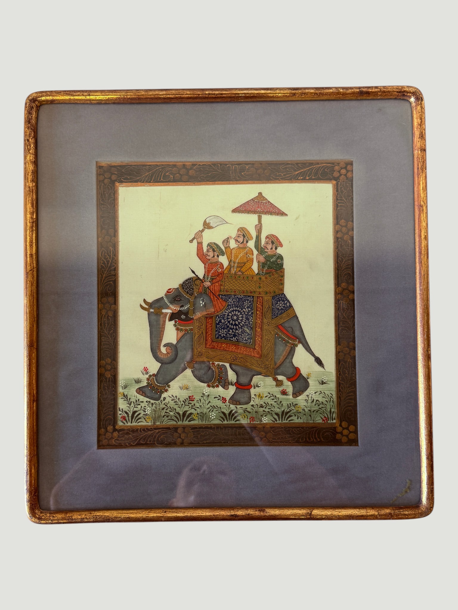 Mughal Style Indian Miniature Painting, Royal Elephant Procession, Framed: A finely detailed Indian miniature painting depicting a royal elephant procession in the Mughal court tradition, featuring richly adorned figures seated atop a caparisoned elephant with elaborate