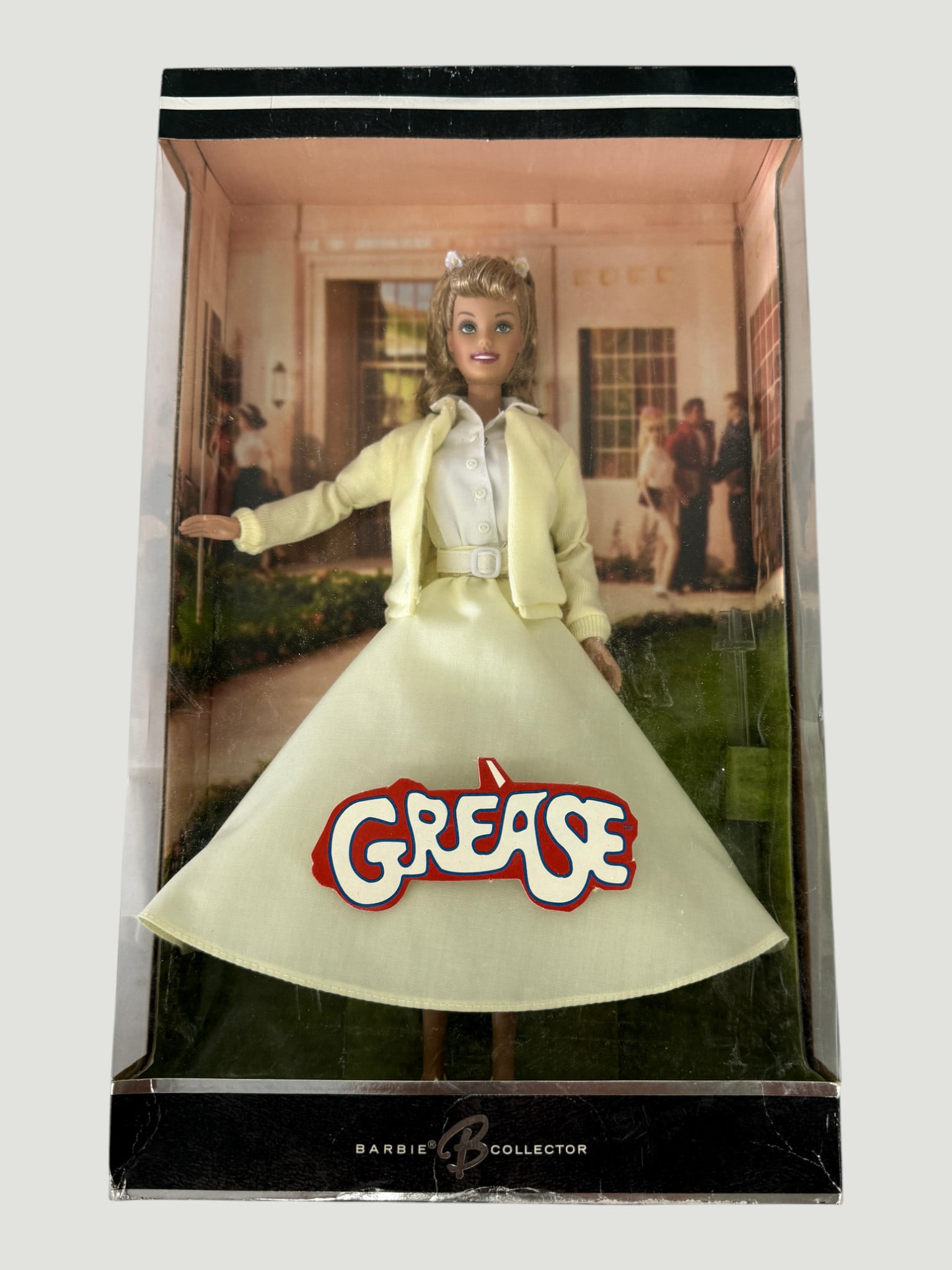 Barbie Collector Grease Sandy Doll in Original Box – Mattel: This is a Mattel Barbie Collector edition Sandy doll from the iconic 1978 film 'Grease,' depicting the character in her classic good-girl outfit featuring a pale yellow cardigan, white blouse, and poo