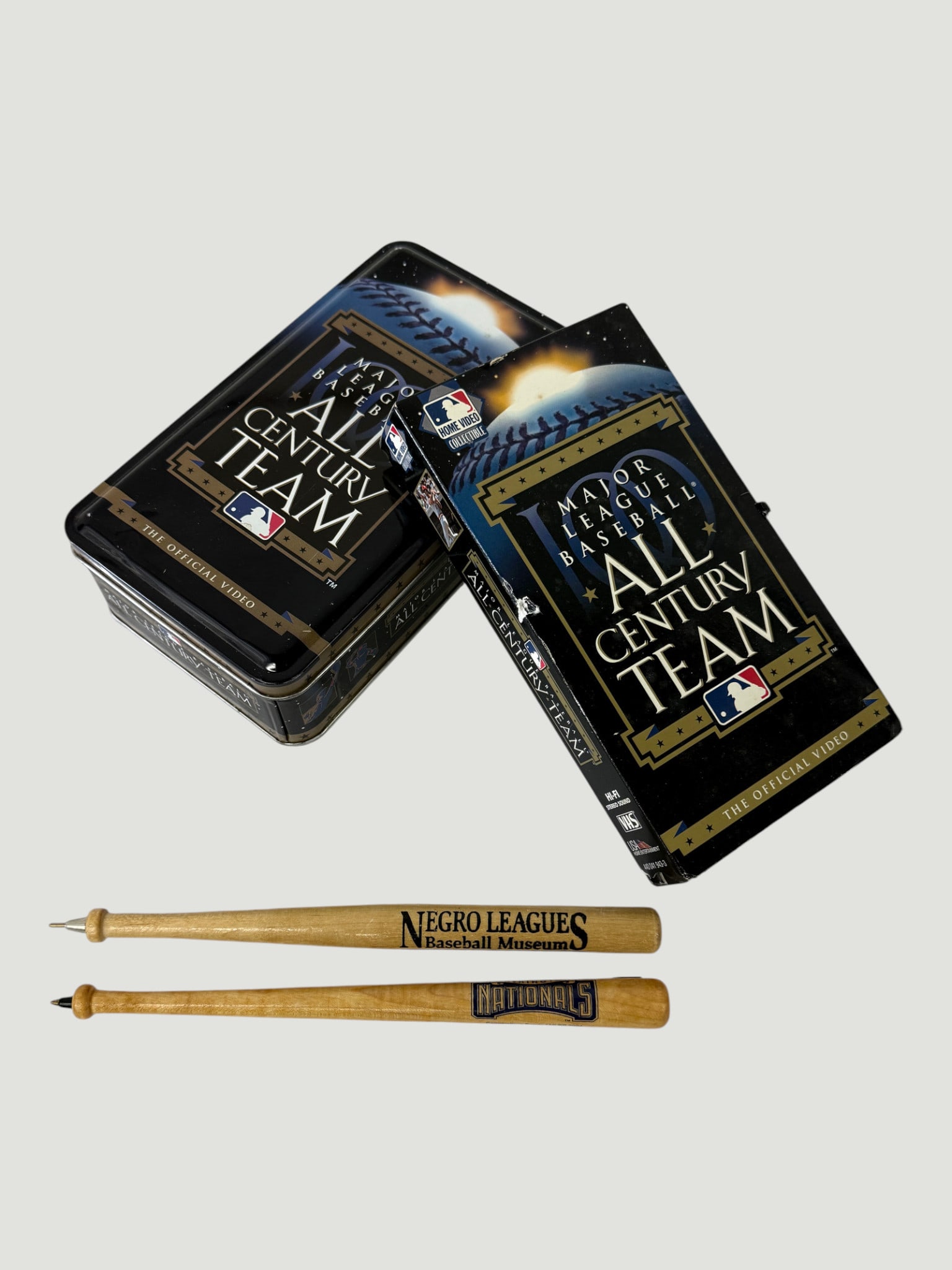 MLB All Century Team VHS Collector's Tin Set & Baseball Bat Pens Memorabilia: This lot comprises the Major League Baseball All Century Team official video release in a commemorative collector's tin, circa 1999, featuring the MLB logo and gold-accented artwork celebrating the sp