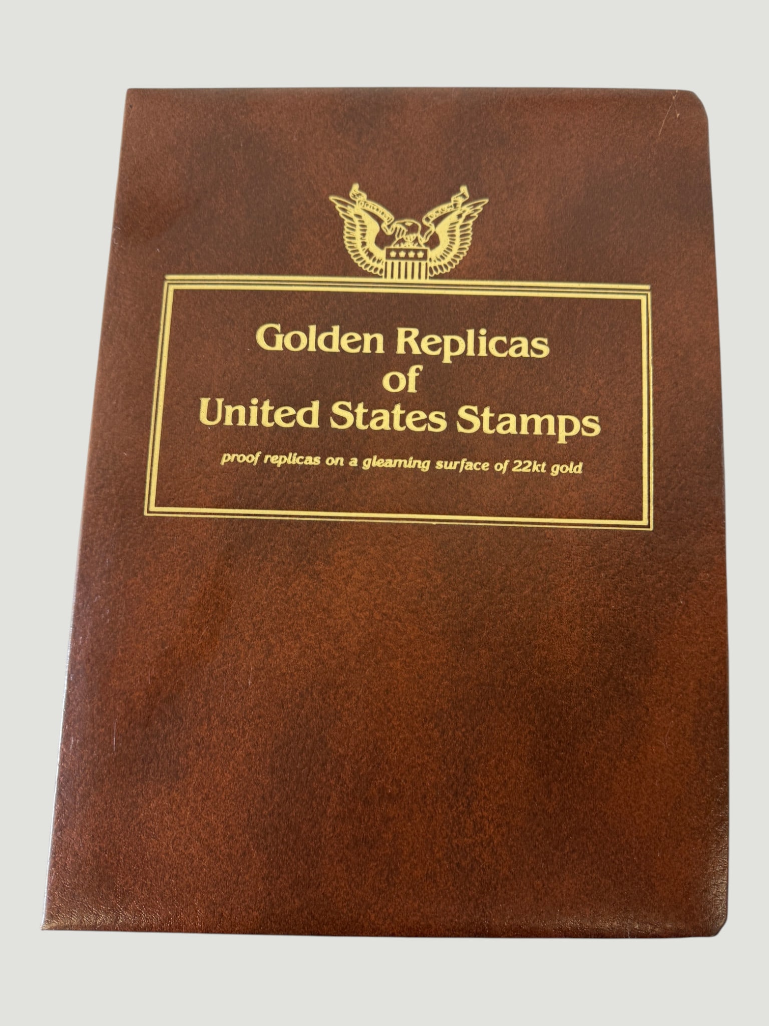 Golden Replicas of United States Stamps 22kt Gold Proof Replica Collection Album: A collector's album titled 'Golden Replicas of United States Stamps,' featuring proof replicas produced on a gleaming surface of 22kt gold. These collectible stamp replicas were produced by the Postal