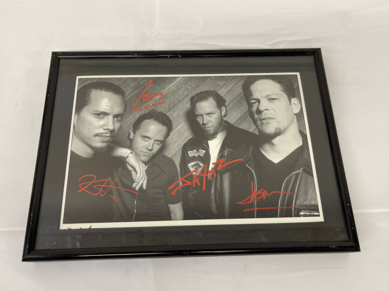 Metallica Band Signed Framed Black & White Photograph, 4 Signatures, c.1990s: A framed black and white promotional photograph featuring four members of the iconic heavy metal band Metallica, bearing four red ink signatures corresponding to each band member pictured. The photo a