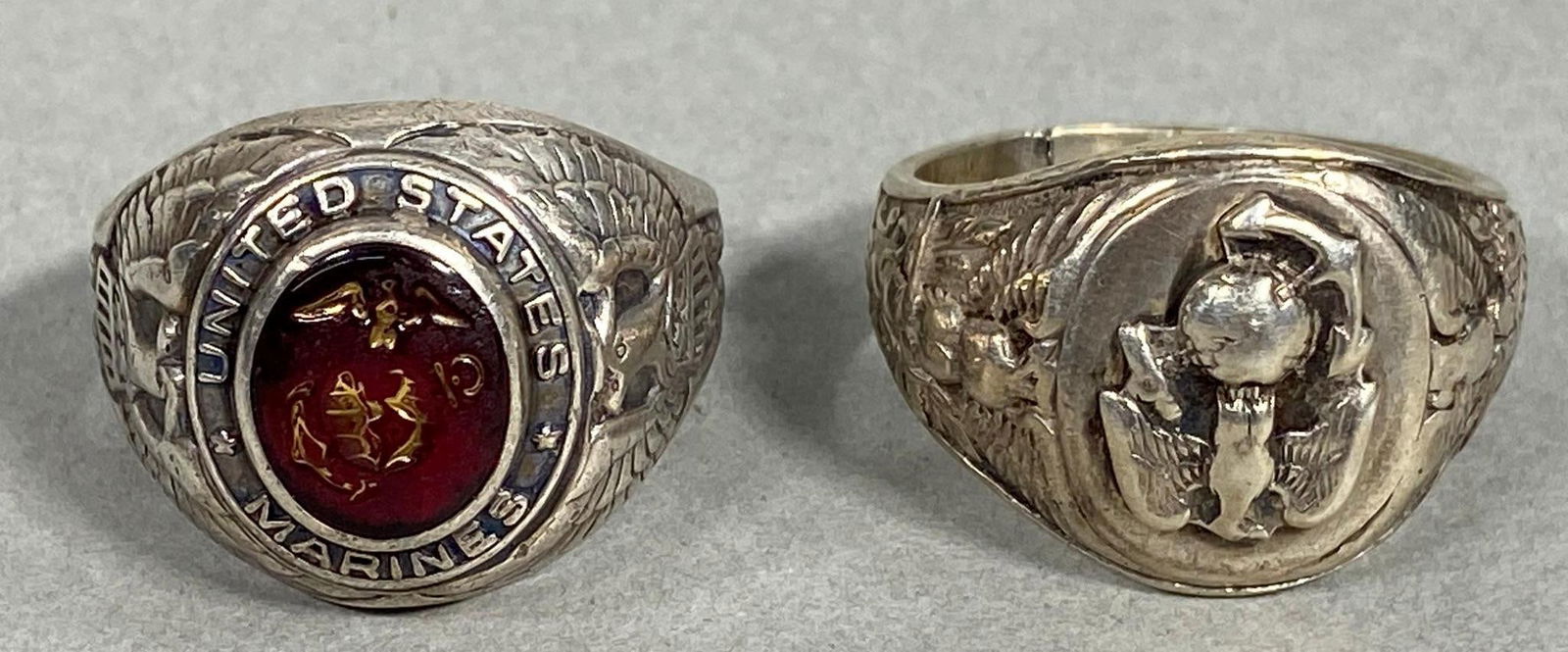 WWII UNITED STATES MARINE CORPS RING LOT (2) USMC: World War Two USMC rings including a sterling marked ring and another with an inset red stone with EGA. The sterling marked ring is a size 12&1/2 and tethering with the inset stone is a size approx 13