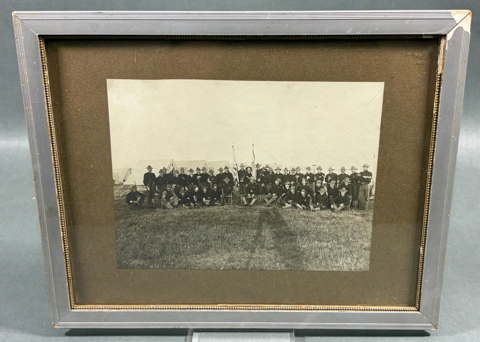 U.S. SPAN-AM WAR PHOTOGRAPH COMPANY OUTDOORS: Outdoor Spanish American War photograph of a company of American soldiers. All of the enlisted men and NCOs are armed with rifles. The entire company wears regulation blue blouses and campaign hats. T