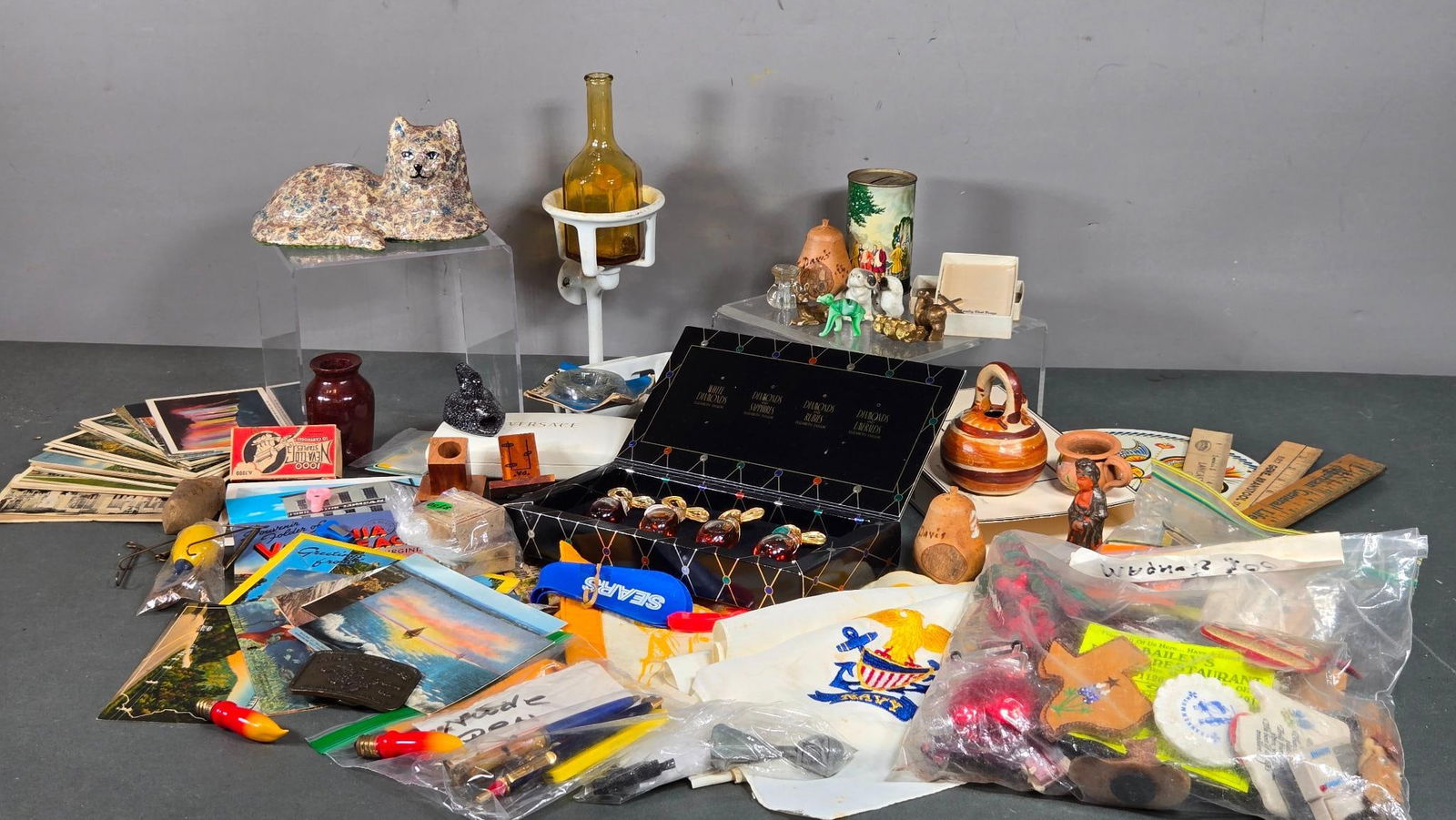 Vintage Elizabeth Taylor Perfume, Pottery Cat, Postcards, Belt Buckle, Small Items More: Bags full of small vintage items. In-house shipping available. Pickup is Thursday, May 29 from from 1 pm to 7 pm at our gallery in Lancaster, OH 43130 or we will provide in-house shipping for this ite