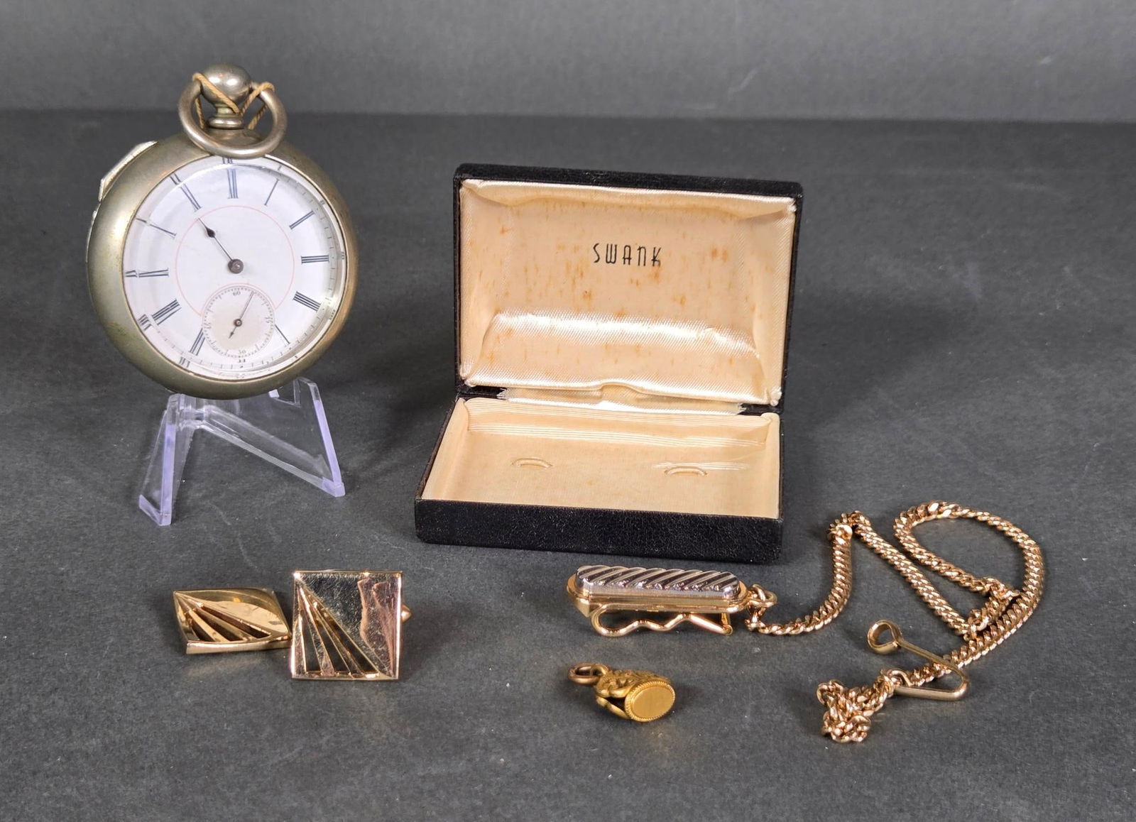 Antique Pocket Watch and Vintage Swank Cufflink Tie Clip Set and Gold Tone Charm: Watch case is 56mm. One cufflink broken. Swank box included. In-house shipping available. Pickup is Thursday, May 29 from from 1 pm to 7 pm at our gallery in Lancaster, OH 43130 or we will provide in-