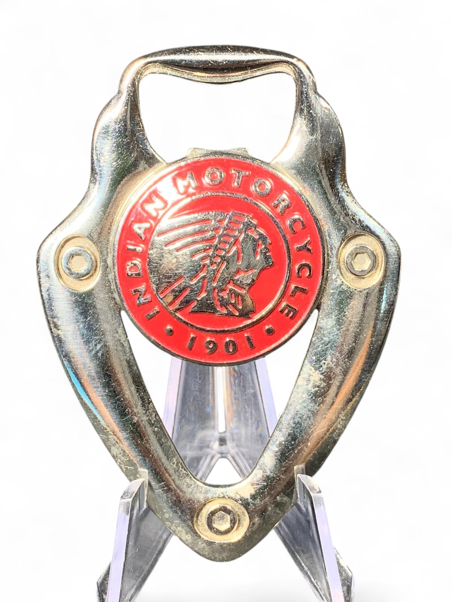 Indian Motorcycle Vintage Style Bottle Opener - Chrome Finish, Red 1901 Emblem, Iconic Chief Logo: This is a metal bottle opener featuring a vintage Indian Motorcycle design. The front displays a prominent red circular emblem with the text 'INDIAN MOTORCYCLE' and '1901' along its border, encircling