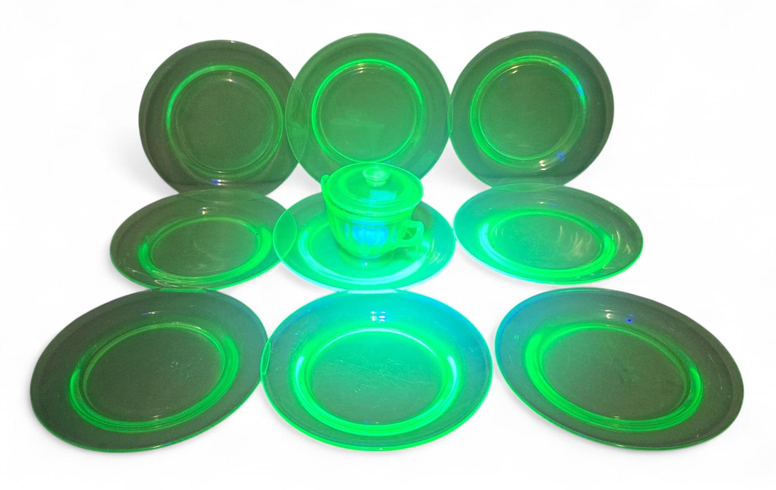 Vintage Uranium Glass Dinnerware Set - Glows Under UV Light, 9 Plates, 1 Lidded Cup, Green: This is a vintage set of uranium glass dinnerware, characterized by its distinctive glow under UV light as seen in one of the images. The collection includes nine matching dinner plates and one lidded