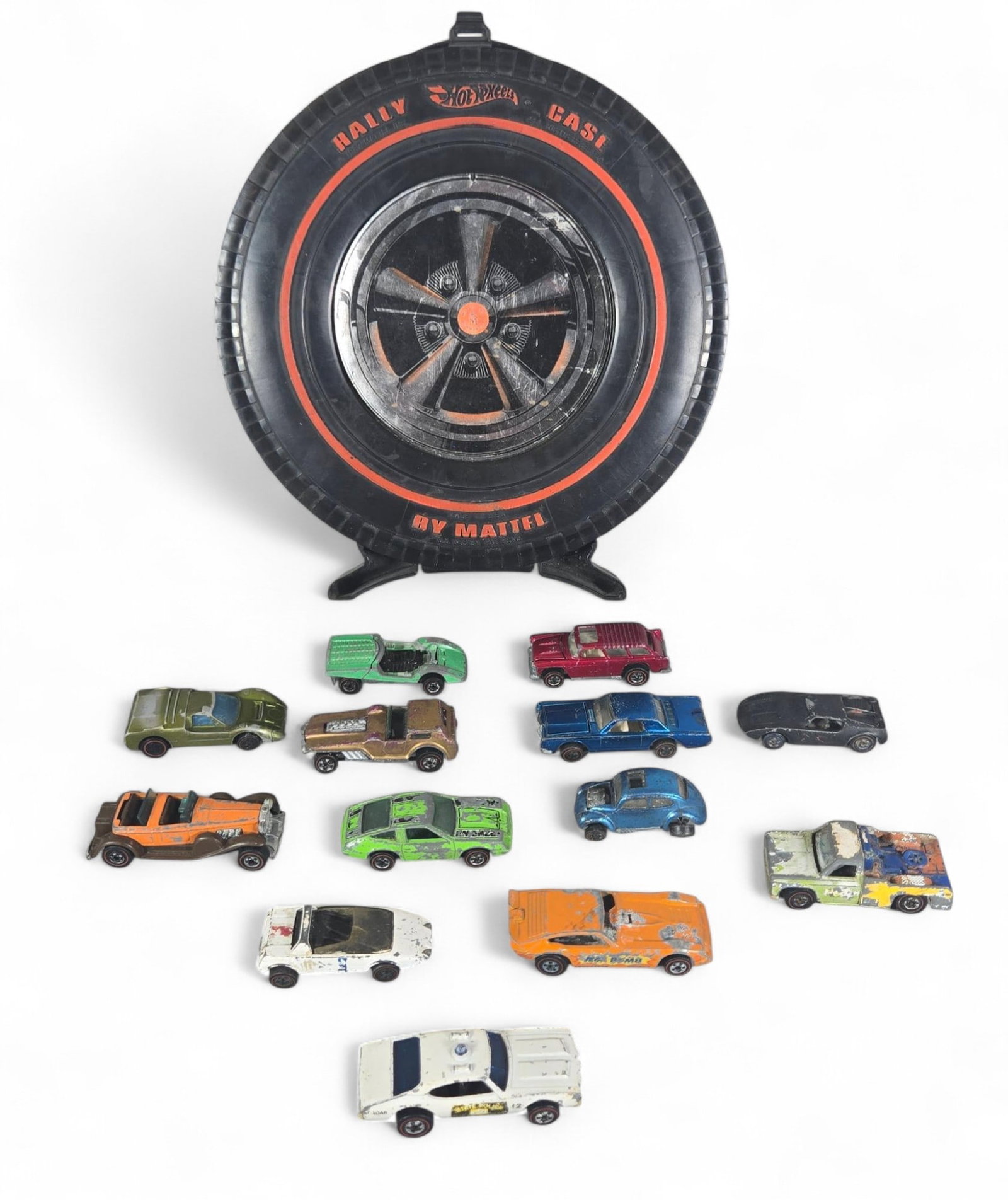 Hot Wheels Rally Case and Die-Cast Cars, Vintage 1969, Redline Wheels, Assorted Models, Black/Assort: This lot features a vintage Hot Wheels Rally Case, manufactured by Mattel in 1969, designed to resemble a classic automotive wheel and tire for convenient storage and transport of toy cars. Accompanyi