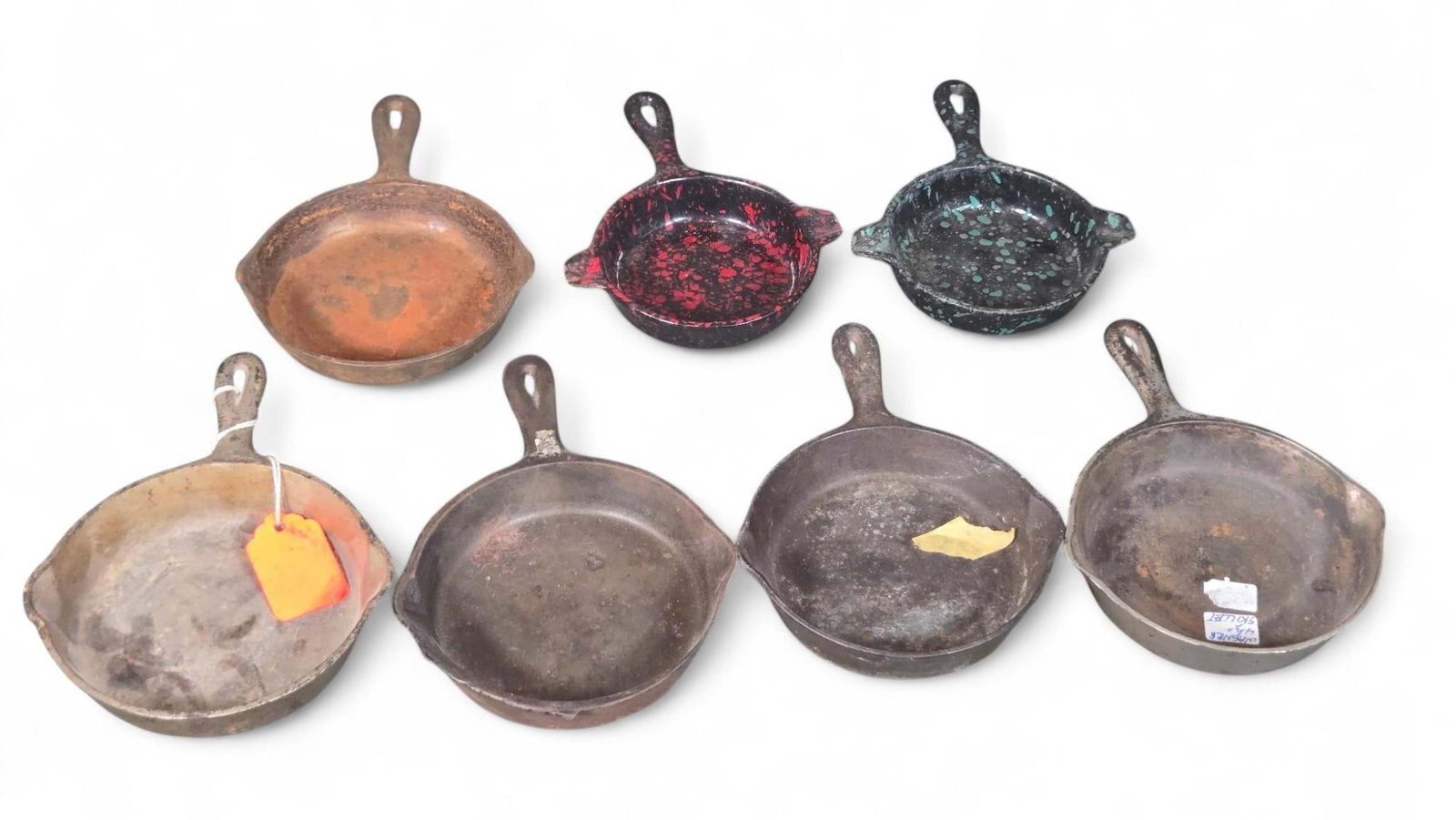 Cast Iron Skillets - Mini Frying Pans, Various Finishes: This lot features a collection of small cast iron skillets. These durable skillets are crafted from cast iron, with some showcasing a traditional plain finish and others adorned with distinctive ename