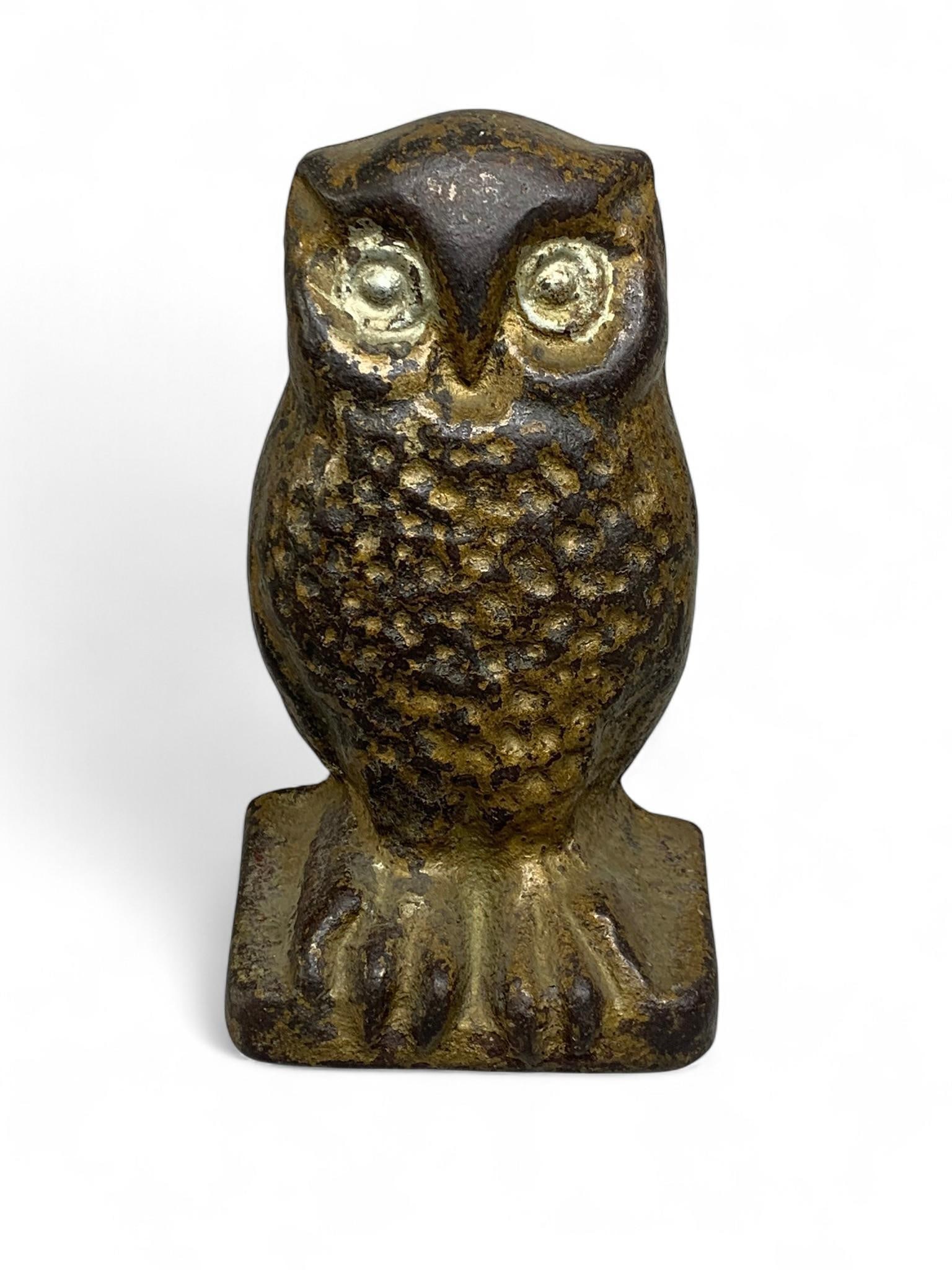 Antique Cast Iron Owl Paperweight: An antique cast iron owl paperweight, featuring a stylized, standing owl figure. The object is crafted from cast iron with a rustic, textured surface and a dark, patinated finish, accented by areas of