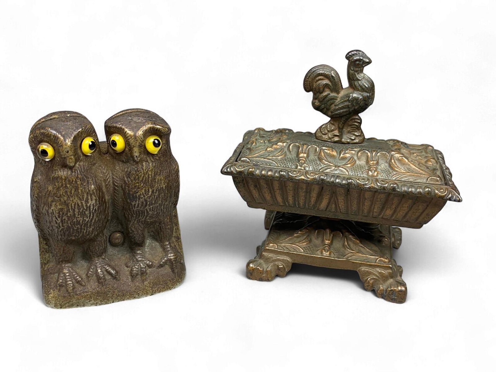 A Group of Patinated Cast Metal Desk Accessories, Late 19th/Early 20th Century: This lot comprises two patinated cast metal desk accessories, likely dating from the late 19th or early 20th century. The first item is a match holder or similar utility piece, featuring stylized owls
