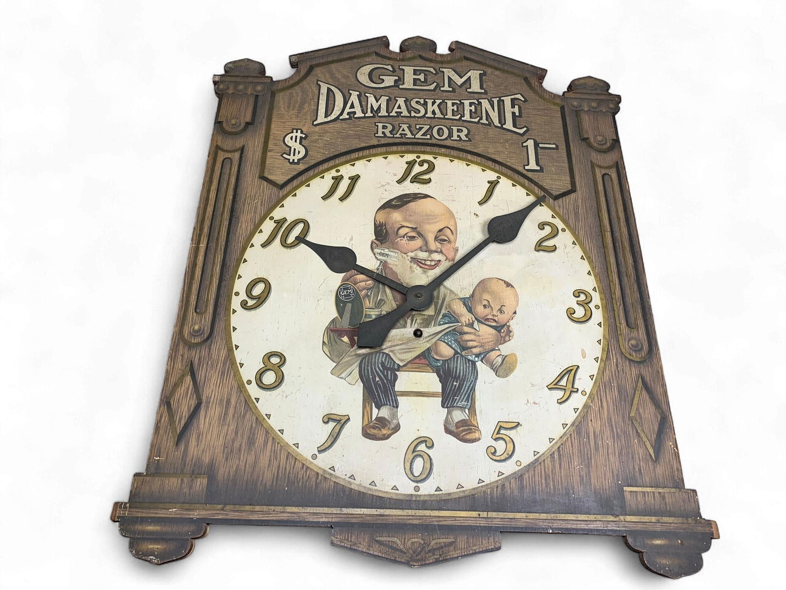 Early 20th Century Gem Damaskeene Razor Advertising Wall Clock by Gem Cutlery Company: An early 20th-century advertising wall clock, featuring a stained wood frame and backboard in a decorative, cut-out shape, promoting the "GEM DAMASKEENE RAZOR." The central clock face is a printed pap