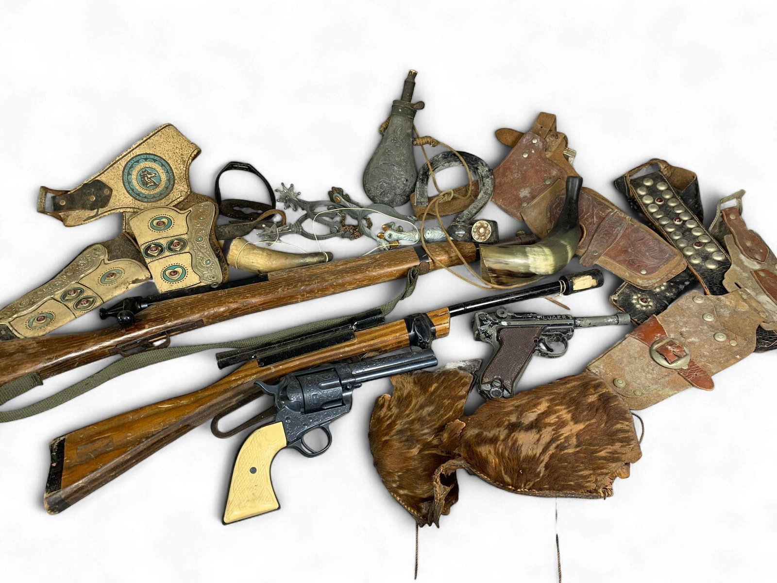 A Collection of Vintage Western-Themed Toy Replicas and Costume Accessories, including a diecast Met: A collection of vintage Western-themed toy replicas and costume accessories. The group includes a diecast metal Luger-style cap pistol, marked 'LUGER,' 'P.08,' and 'CAL. 9mm,' consistent with vintage 
