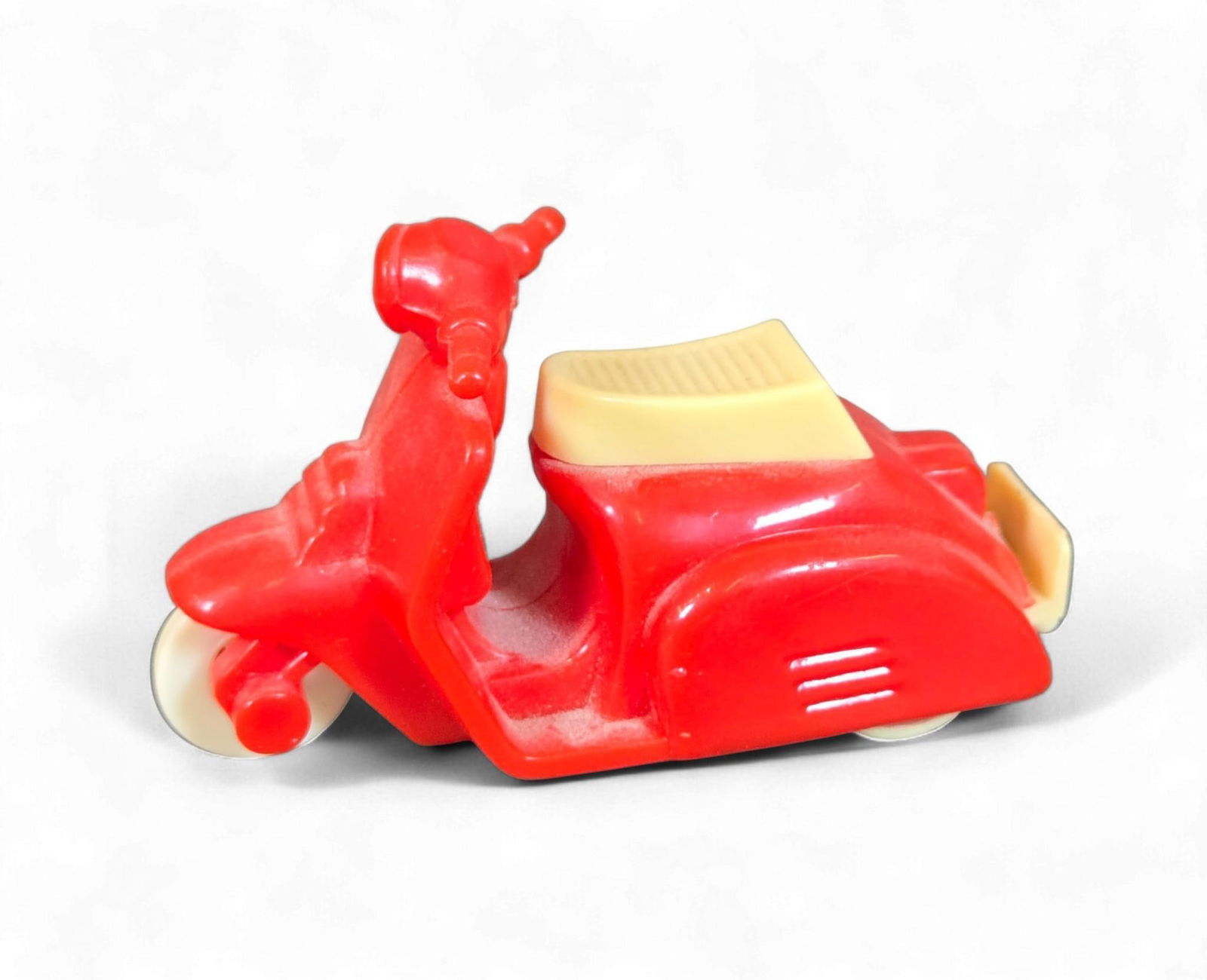 Vintage Maple Town Vespa-Style Miniature Plastic Toy Scooter: A vintage Maple Town Vespa-style miniature toy scooter, molded primarily from red plastic with a cream-colored seat and white wheels. The design is a simplified representation of a classic motor scoot