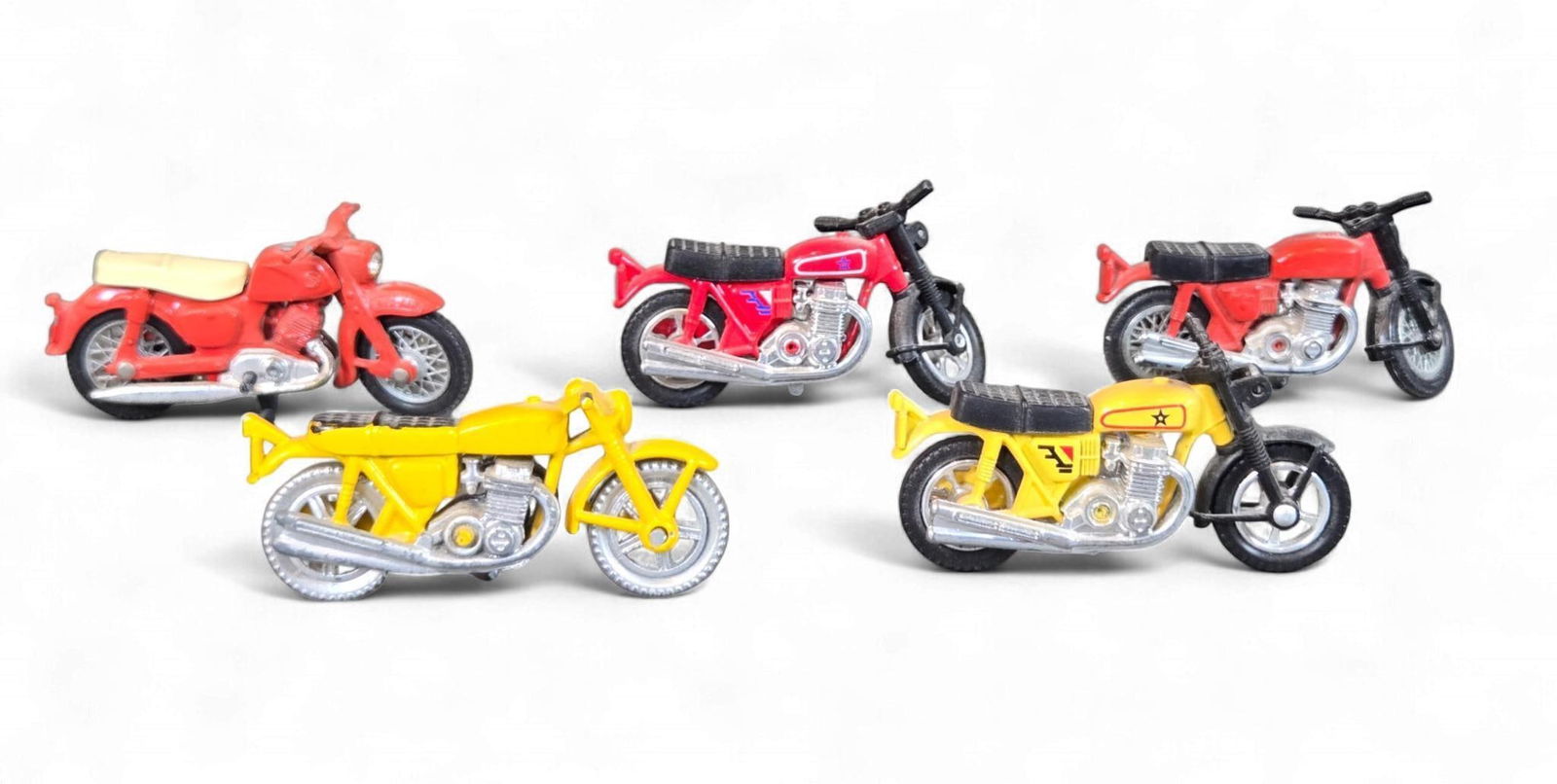 A Group of diecast Toy Motorcycles, including a Matchbox Series No. 38 by Lesney and four Honda-styl: This lot comprises five small-scale diecast toy motorcycles. One vintage red diecast toy motorcycle, approximately 2.5 inches in length, features a cream/yellow plastic seat. The front fender is embos