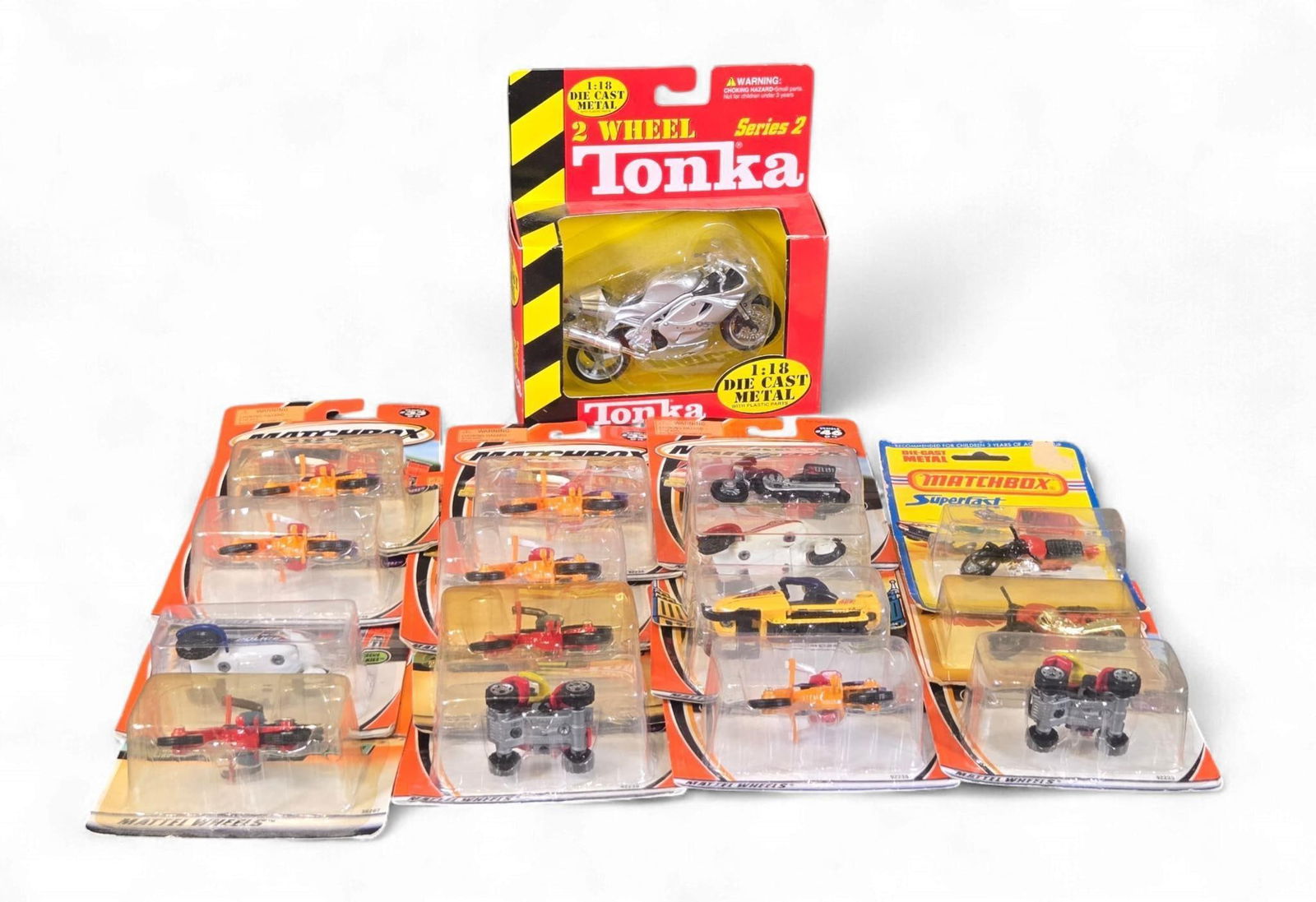 A 2000 Maisto 2 Wheel Tonka 1:18 Silver Triumph 955i Daytona Motorcycle and a Collection of Matchbox: This lot comprises a 2000 Maisto 2 Wheel Tonka 1:18 scale silver Triumph 955i Daytona diecast metal motorcycle, presented in its original cardboard box. Accompanying this is a collection of smaller di