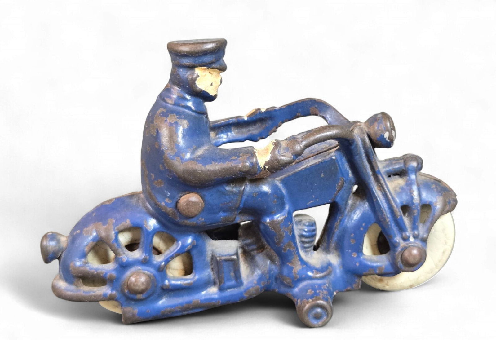 A Champion Cast Iron Police Motorcycle Toy, circa 1930s: A Champion Cast Iron Police Motorcycle Toy, circa 1930s. This vintage toy motorcycle features an integrated rider, cast from a dark, heavy metal, consistent with cast iron. The piece is predominantly