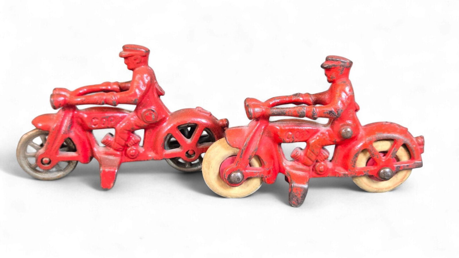 A Group of Hubley Cast Iron "Cop" Motorcycles, circa 1930s-40s: A Group of Hubley cast iron toy motorcycles, depicting uniformed police officers, dating from the 1930s-40s. Each motorcycle is painted red and features an embossed "COP" on its side. One motorcycle i