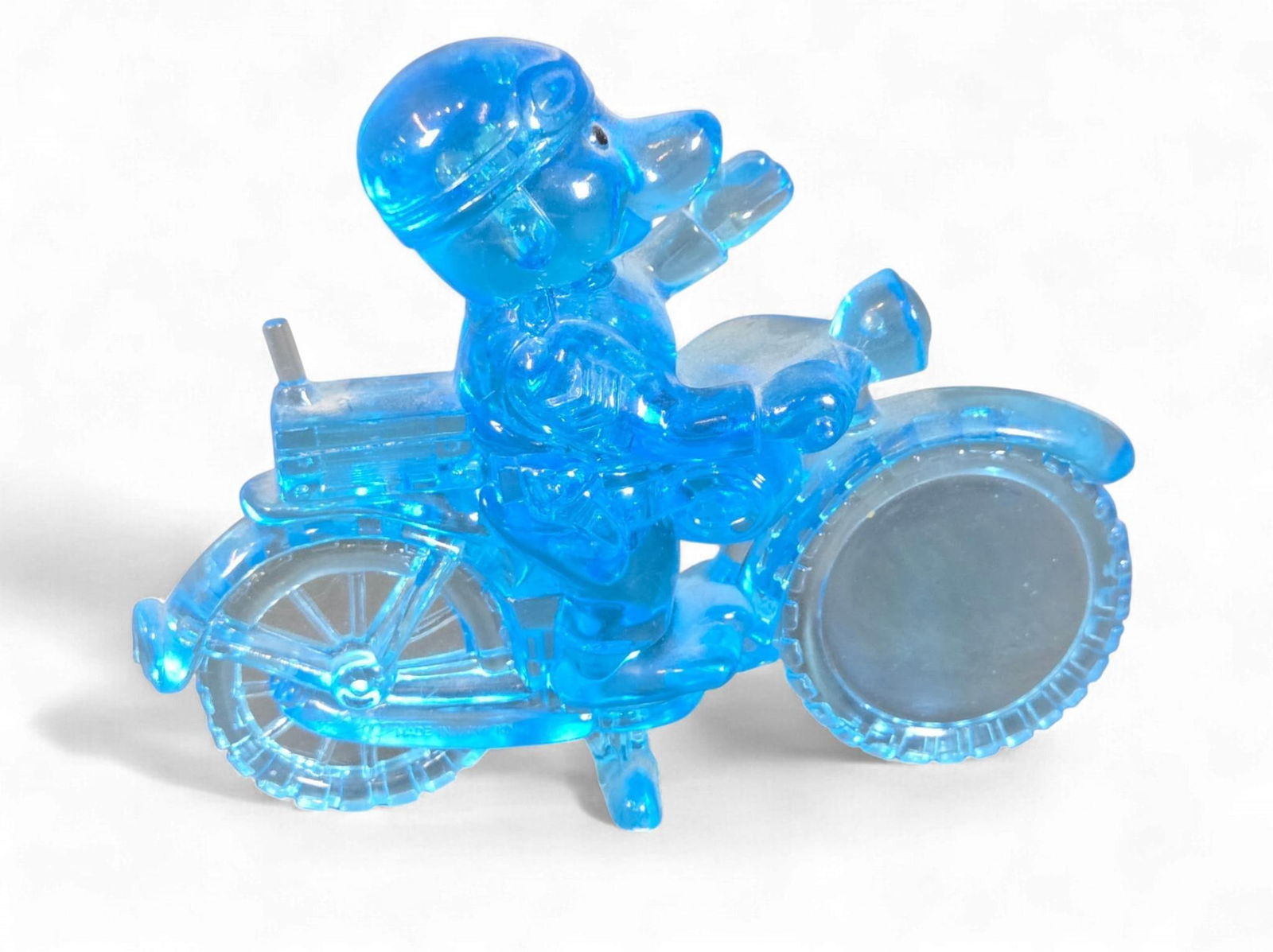 Vintage Plastic Motorcycle Riding Police Dog Magnifying Glass: A vintage plastic novelty magnifying glass depicting an anthropomorphic character, resembling a dog, wearing a helmet and goggles, riding a stylized motorcycle. Crafted from translucent blue plastic,