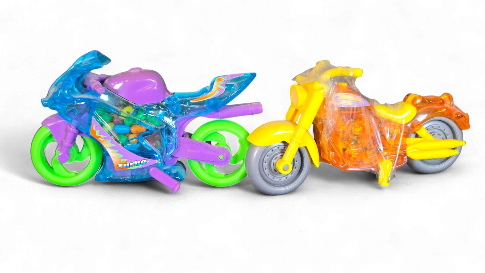 A Group of Late 20th/Early 21st Century Plastic Toy Motorcycle Candy Dispensers: A Group of brightly colored, translucent plastic toy motorcycles, designed as candy dispensers. The left motorcycle features a sporty design in blue, purple, and neon green, with "Turbo" in a stylized
