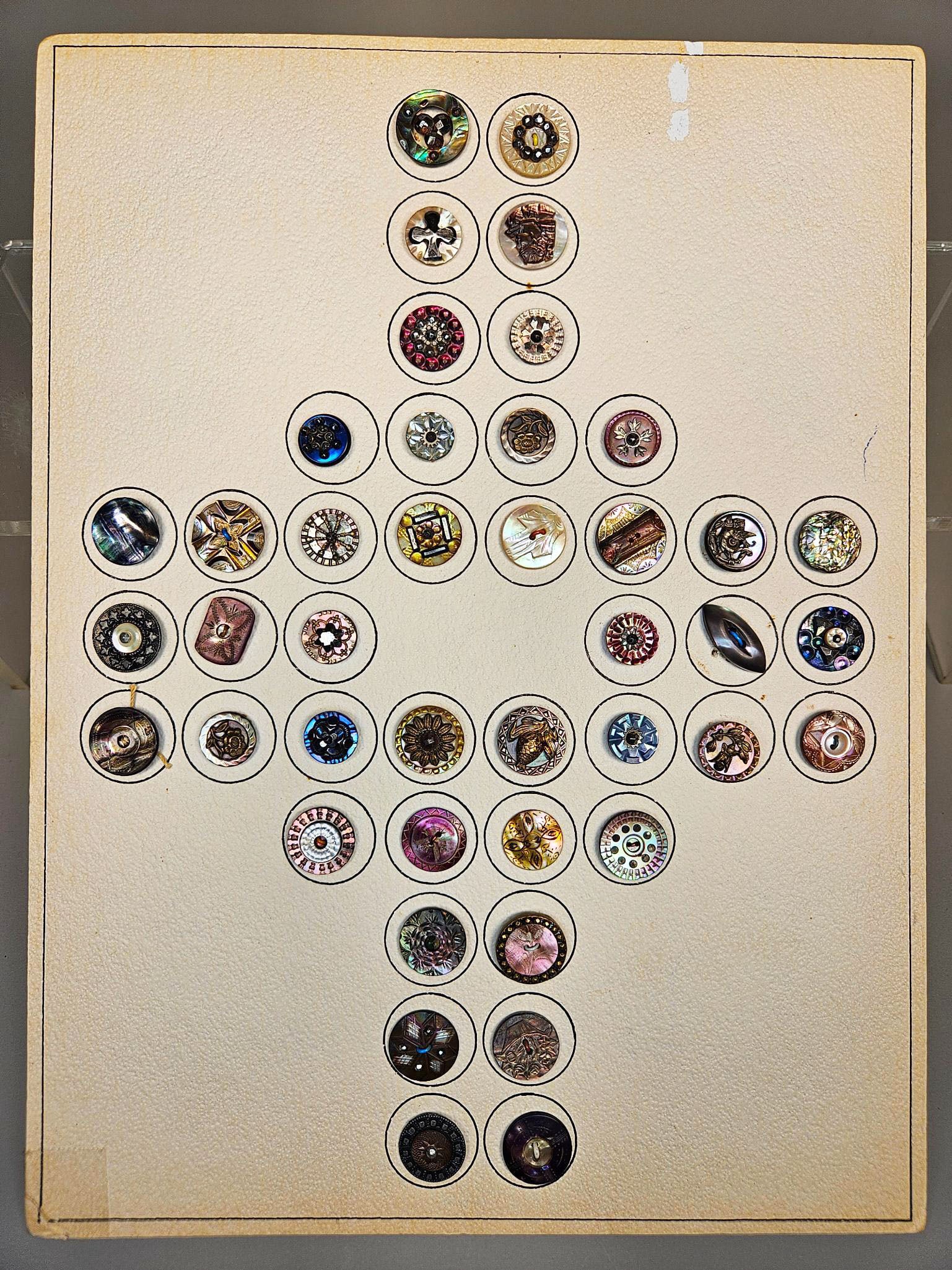 A group of Vintage and Antique Mother-of-Pearl and Abalone Buttons: A group of vintage and antique buttons, primarily crafted from iridescent mother-of-pearl, abalone, or nacre. These buttons are often accented with metallic components in gold-tone, silver-tone, or br