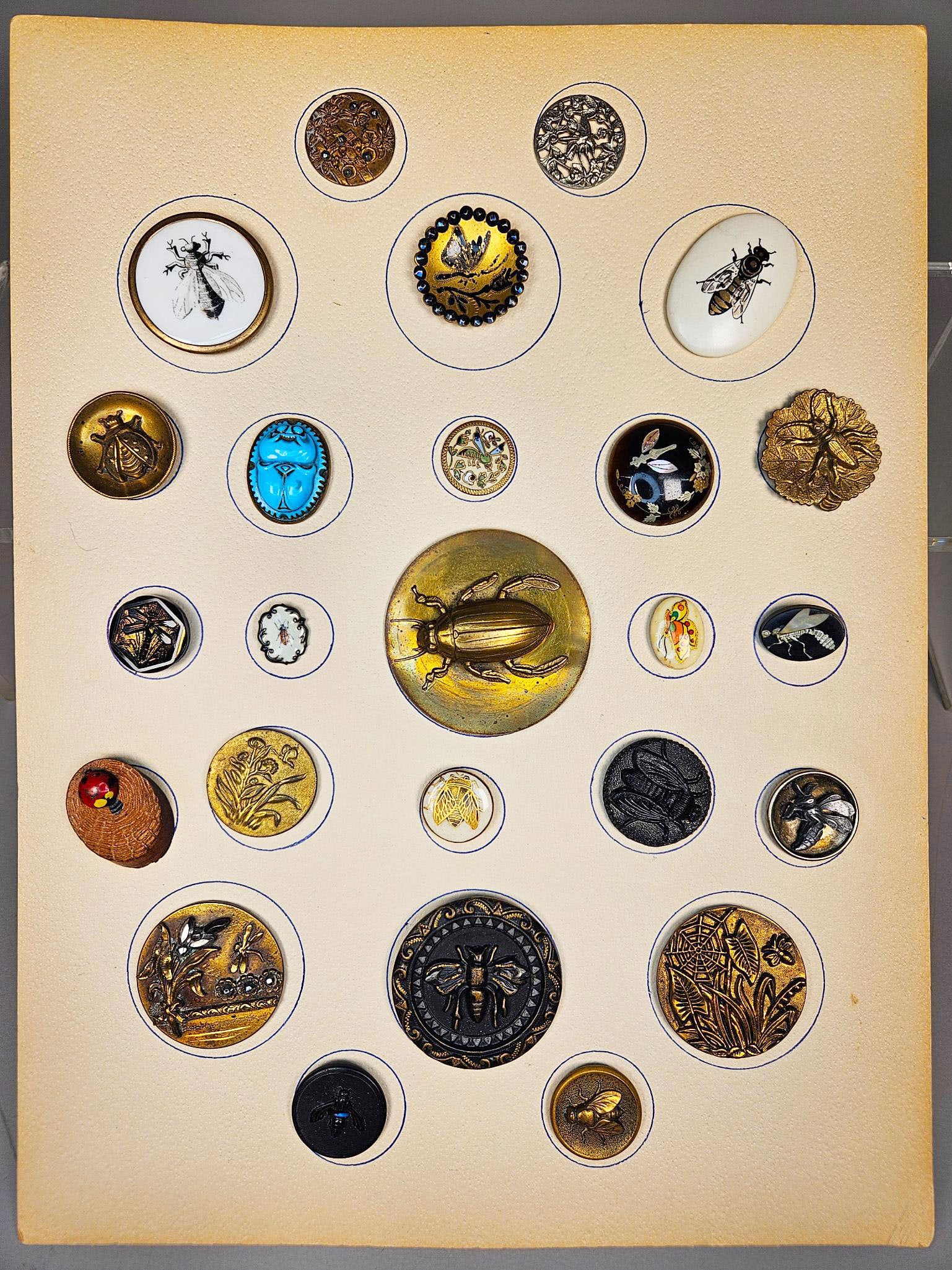 A group of Late Victorian to Art Nouveau Entomological and Naturalistic Buttons: A group of antique or vintage buttons, predominantly featuring entomological and naturalistic motifs such as bees, beetles, flies, butterflies, and botanical elements. The buttons are crafted from div