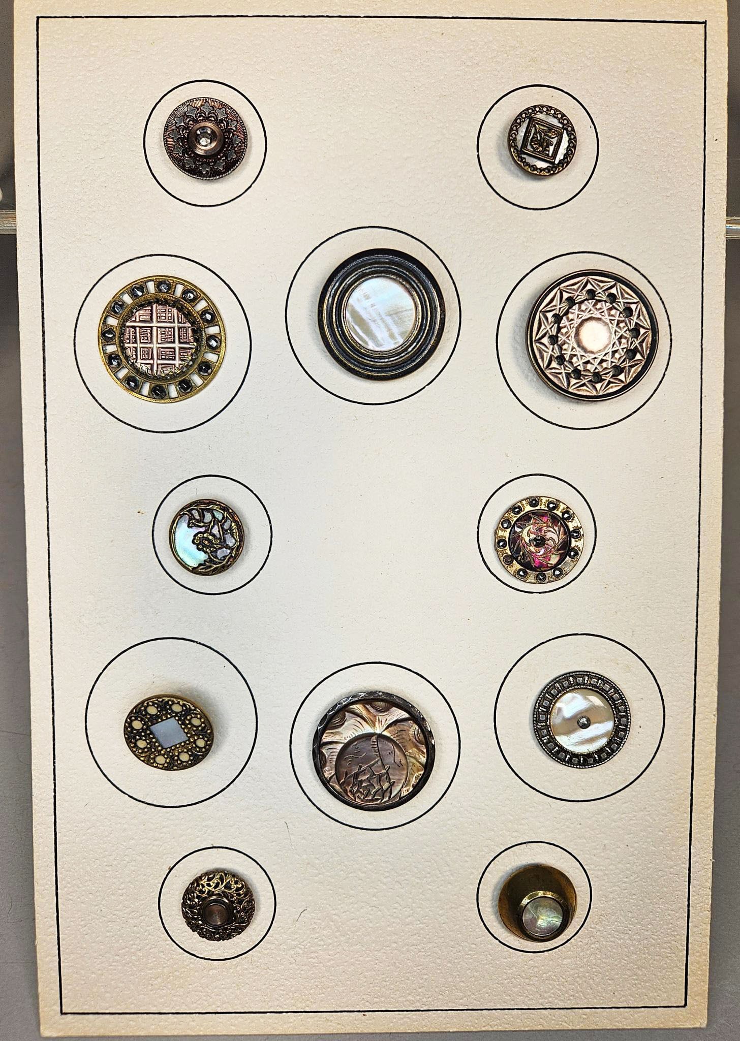 A group of Art Deco Style Abalone and Mother-of-Pearl Buttons: This lot comprises group of predominantly round buttons, showcasing diverse styles and materials. The buttons feature materials such as iridescent mother-of-pearl, various bronze-tone and silver-tone