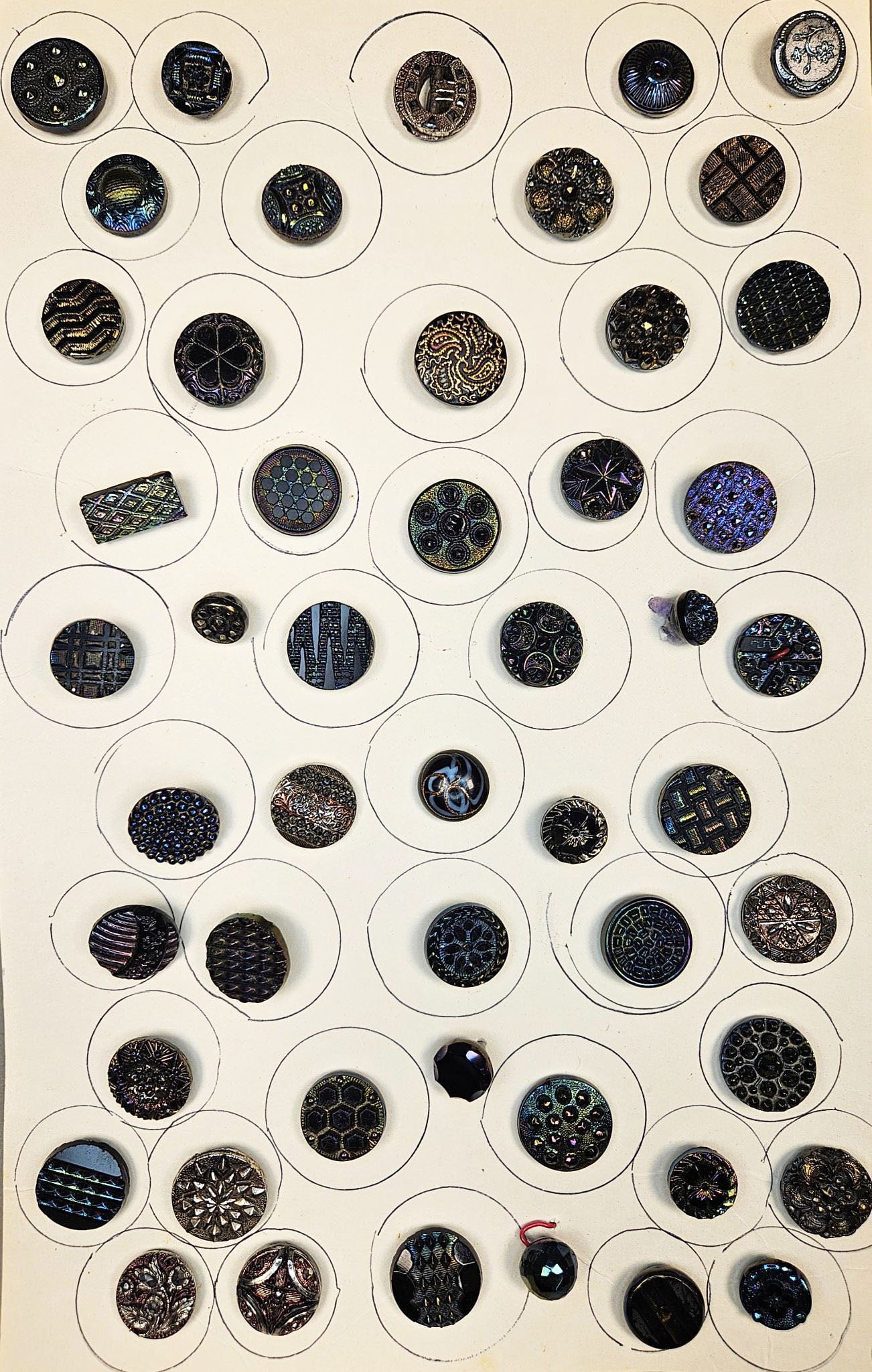 A group of Antique or Vintage Iridescent Lustre Glass Buttons: A diverse group of antique or vintage buttons, primarily crafted from iridescent or "lustre" glass. The buttons display a wide variety of styles, including geometric patterns such as grids, hexagons, 