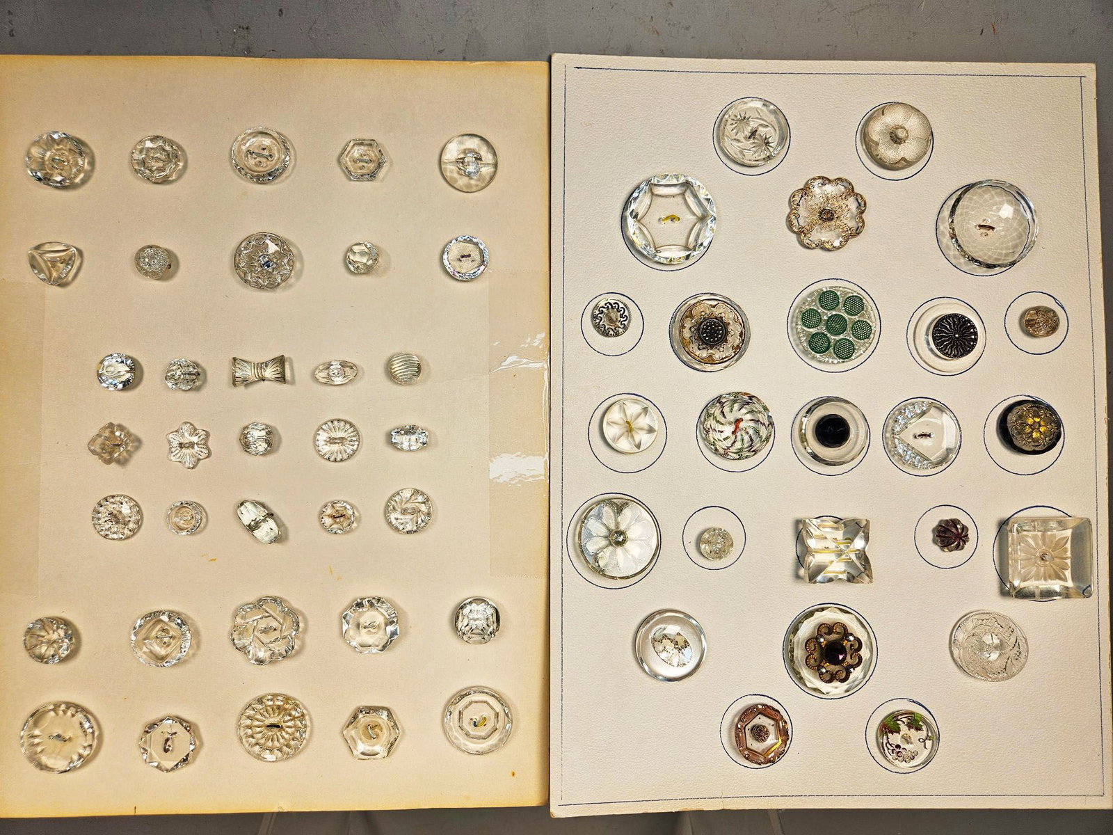 A group of Antique and Vintage Glass and Composite Buttons: A group of antique and vintage buttons, predominantly mounted on group of off-white cardboard display cards, with an additional card showcasing various small, coiled wire button shanks or attachments.