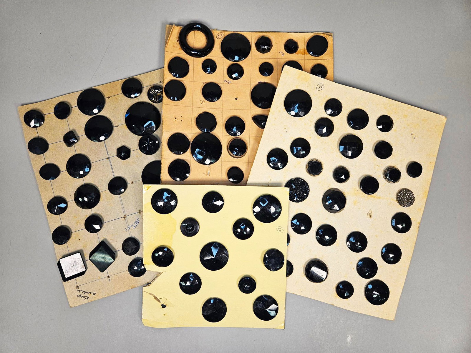 A group of Vintage and Antique Black Buttons on group of Display Cards: A group of vintage and antique black buttons presented on group of cardboard display cards. The buttons exhibit a variety of sizes and forms, including faceted rounds, ovals, hexagons, squares, and a