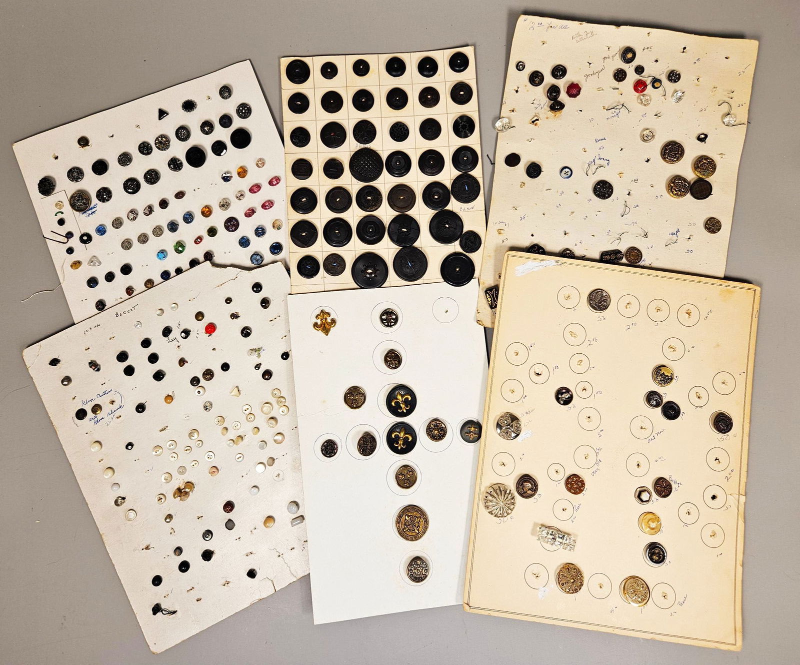 A Collection of Late 19th to Early 20th Century Mother-of-Pearl, Glass, Metal, and Early Plastic: A diverse collection of several group of antique and vintage buttons, meticulously displayed across multiple aged cardboard inventory sheets. The buttons, dating from the late 19th to early 20th centu