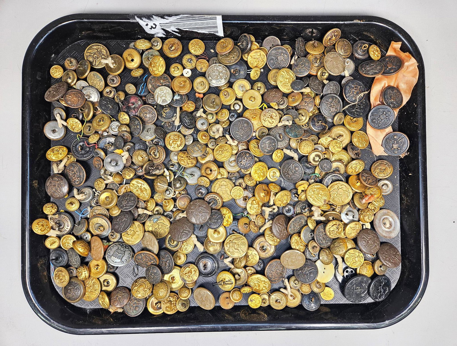 A Substantial Collection of American Military and Uniform Buttons, Late 19th to Mid-20th Century: A substantial quantity of assorted buttons, predominantly crafted from brass or bronze in various shades of gold and darkened patina. The collection also includes examples made of dark brown horn or h