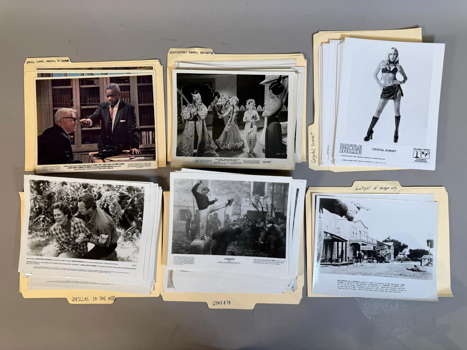 A Collection of Vintage and Contemporary Movie Press Stills: A collection of movie press stills, predominantly 8x10 inches, organized within manila folders with handwritten labels for various film productions including "GUESS WHO'S COMING TO DINNER," "GENTLEMEN