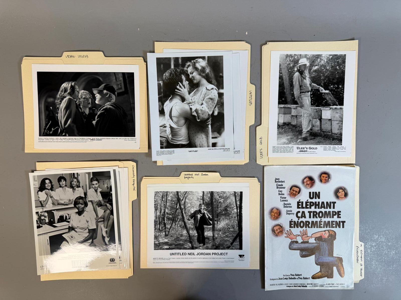 A Collection of Late 20th Century Film and Television Promotional Stills and a French Film Poster: A collection of promotional materials, primarily comprised of numerous black and white photographic prints and color film poster, organized within manila folders. The photographs are generally glossy